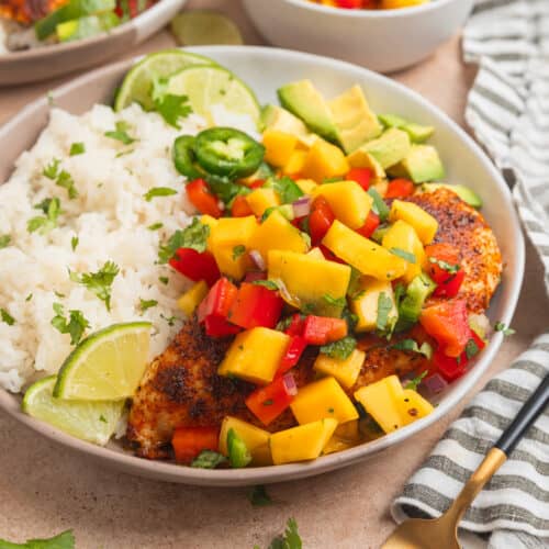 Mango salsa chicken served on plate with white rice and lime.