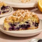 Slice of blueberry lemon coffee cake on plate with icing drizzle on top.