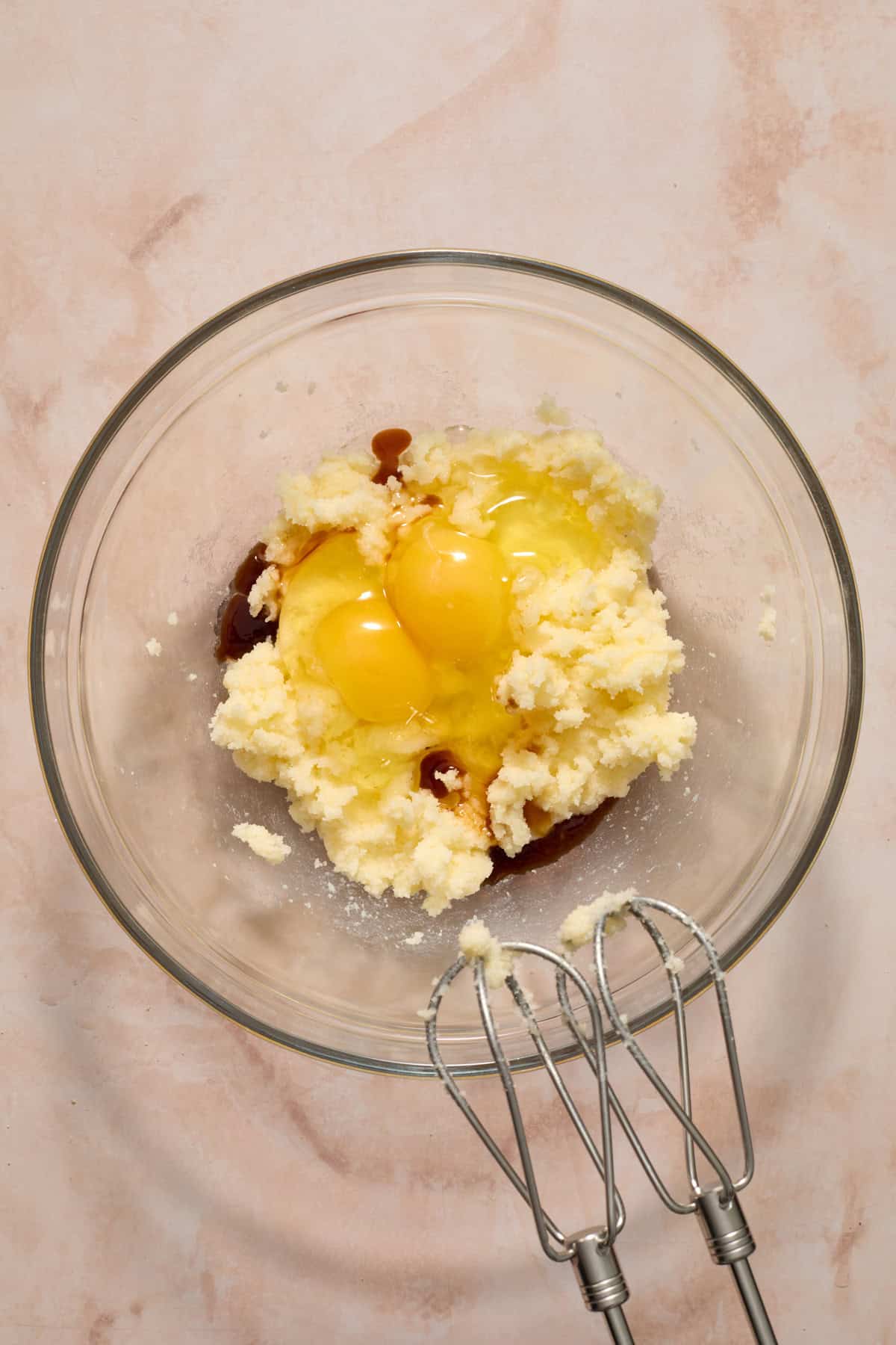Creamed butter and sugar in bowl with eggs and vanilla added.