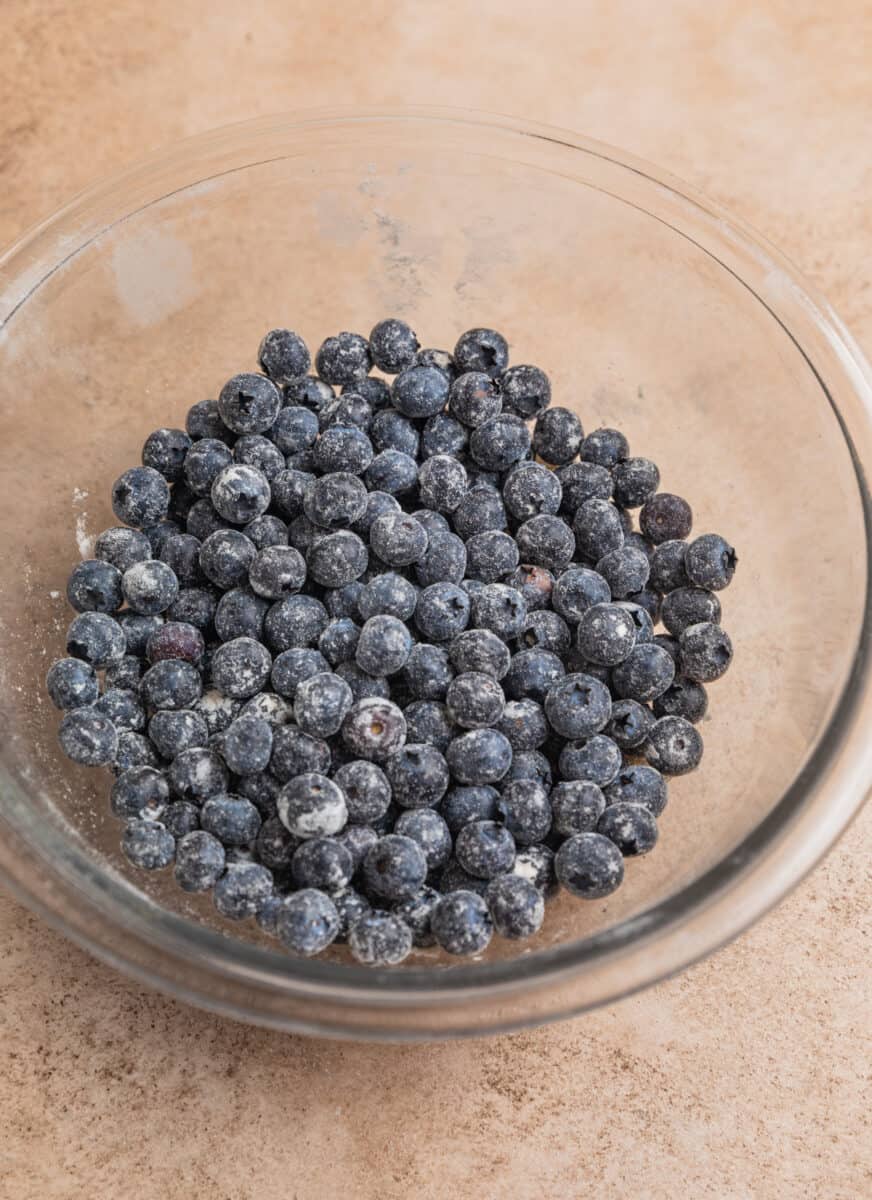 Blueberries dusted in flour in glass mixing bowl.