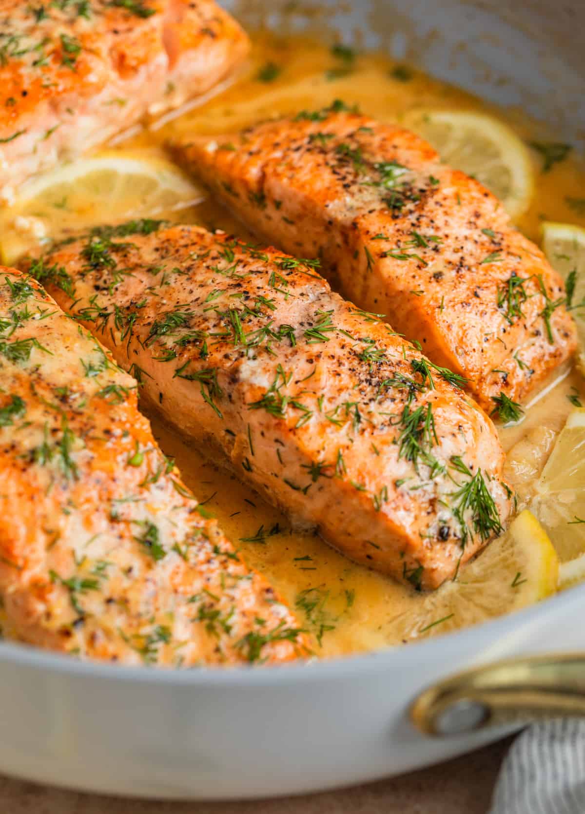 Salmon in skillet with lemons and topped with chopped dill.