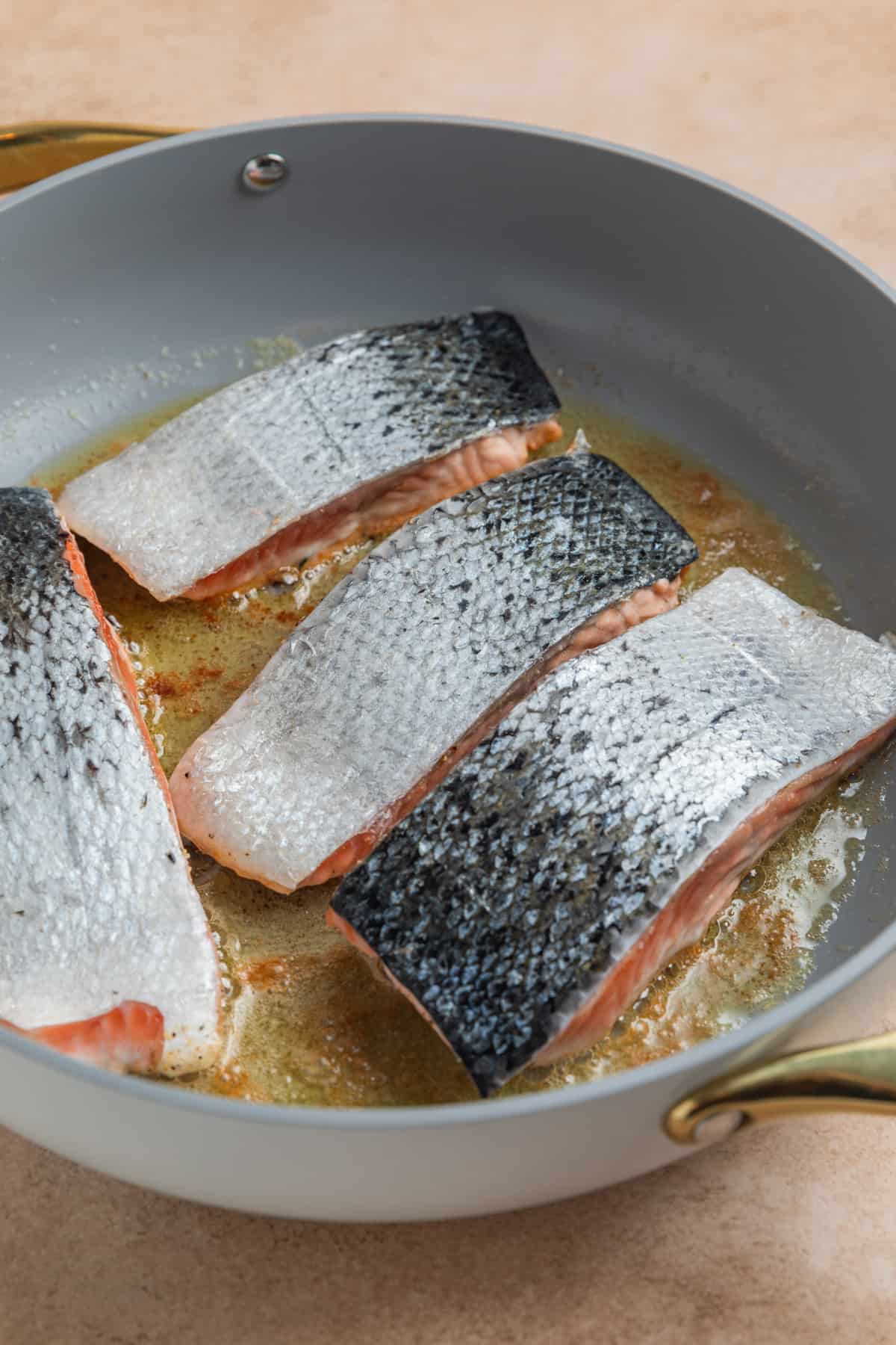 Salmon filets in skillet with skin up.