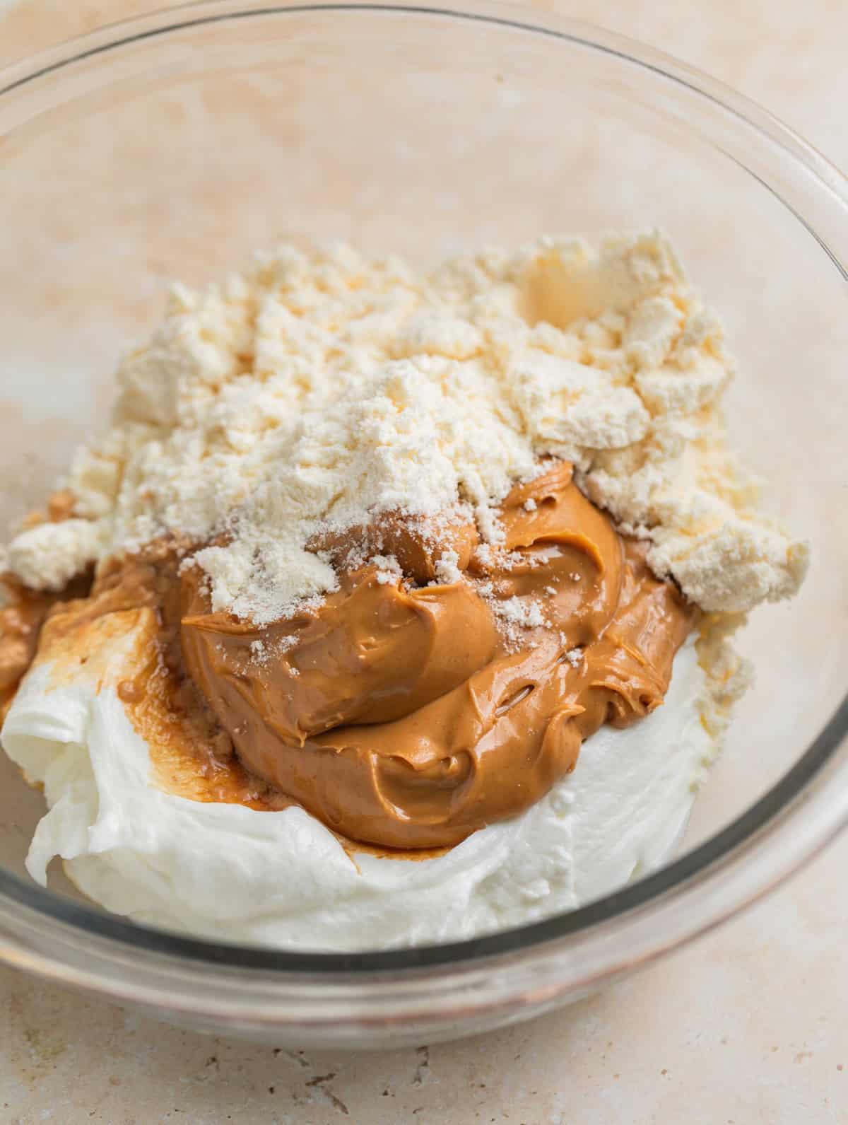 Peanut butter, plain Greek yogurt, protein powder and vanilla in glass mixing bowl.