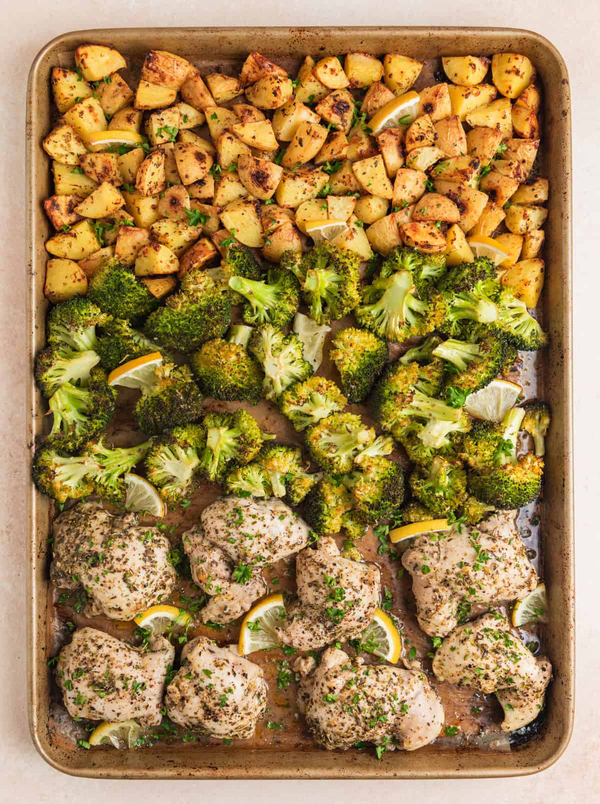 Sheet pan chicken and broccoli with potatoes arranged on baking sheet.