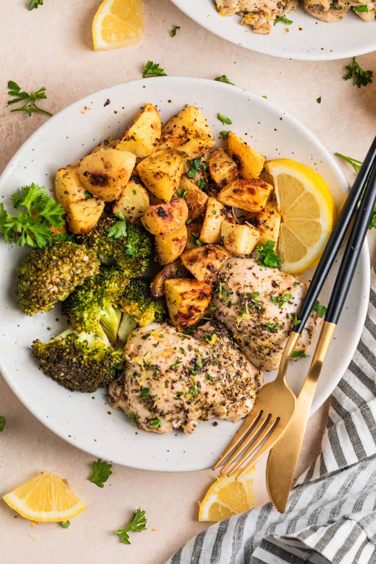 Overhead view of one pan lemon garlic chicken with broccoli and roasted potatoes on white plate.