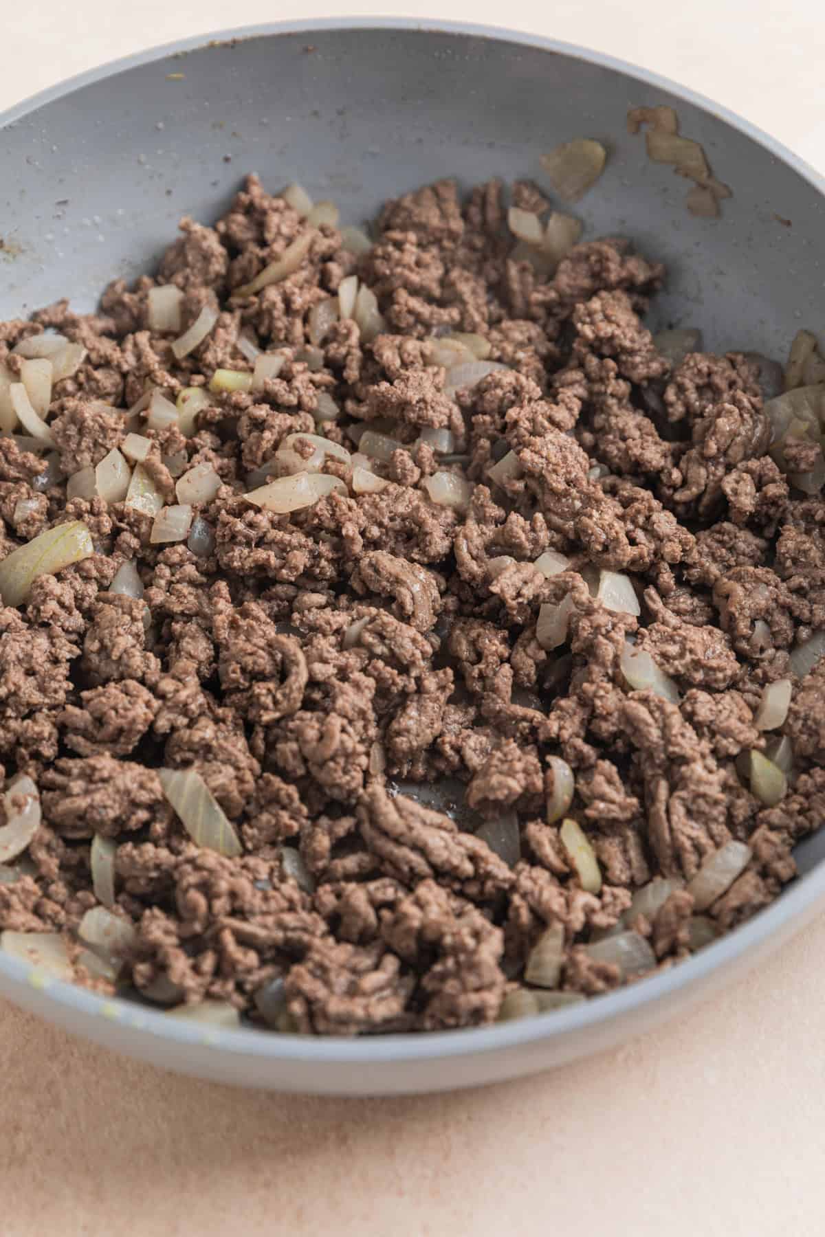 Ground beef and onions cooked in skillet.