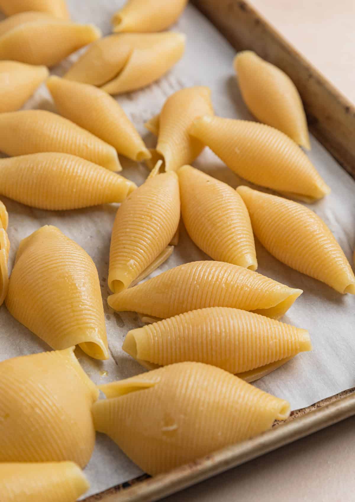 Jumbo pasta shells on parchment lined baking sheet.