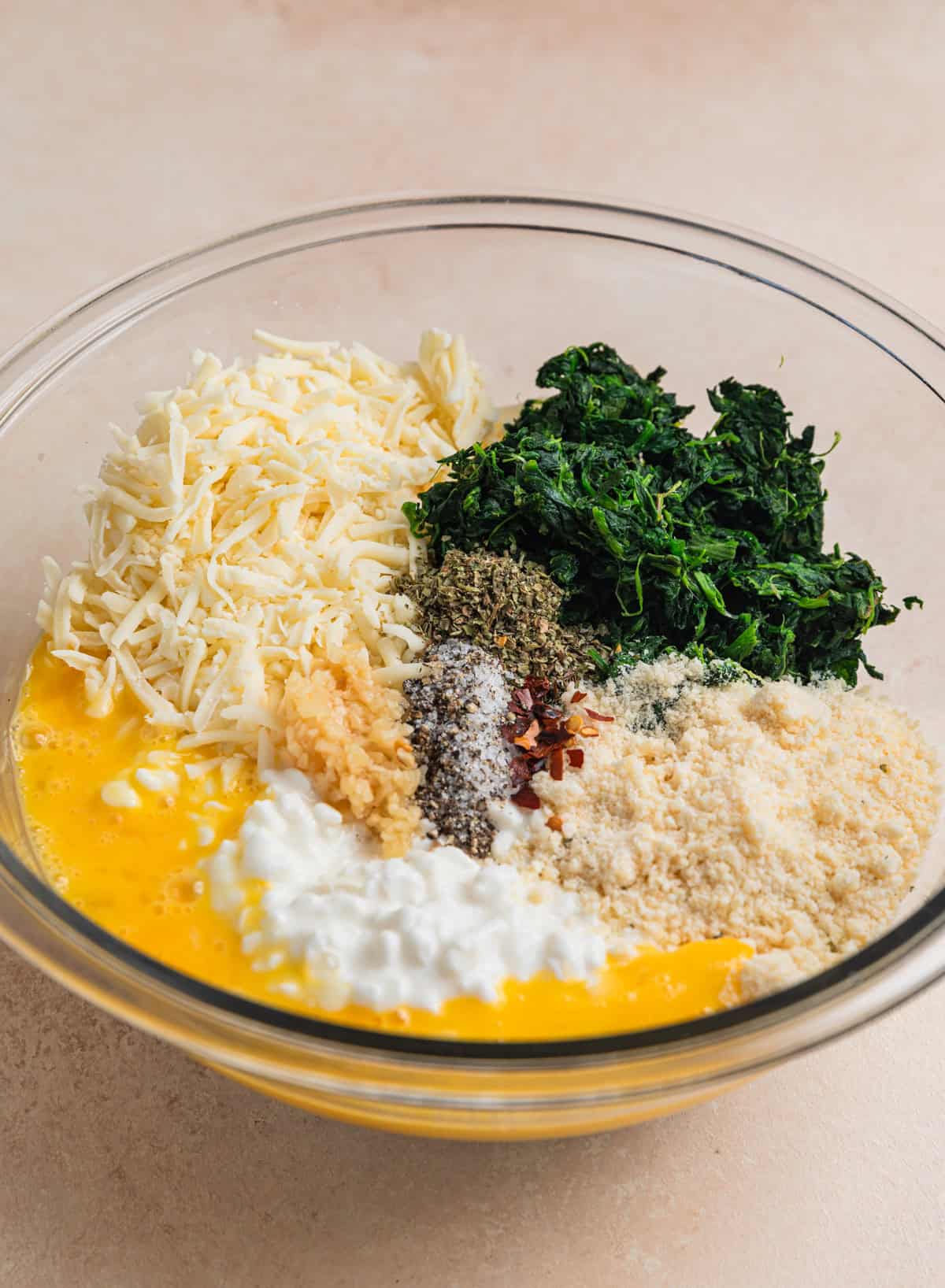 Egg, cottage cheese, mozzarella, spinach, and seasoning in mixing bowl.
