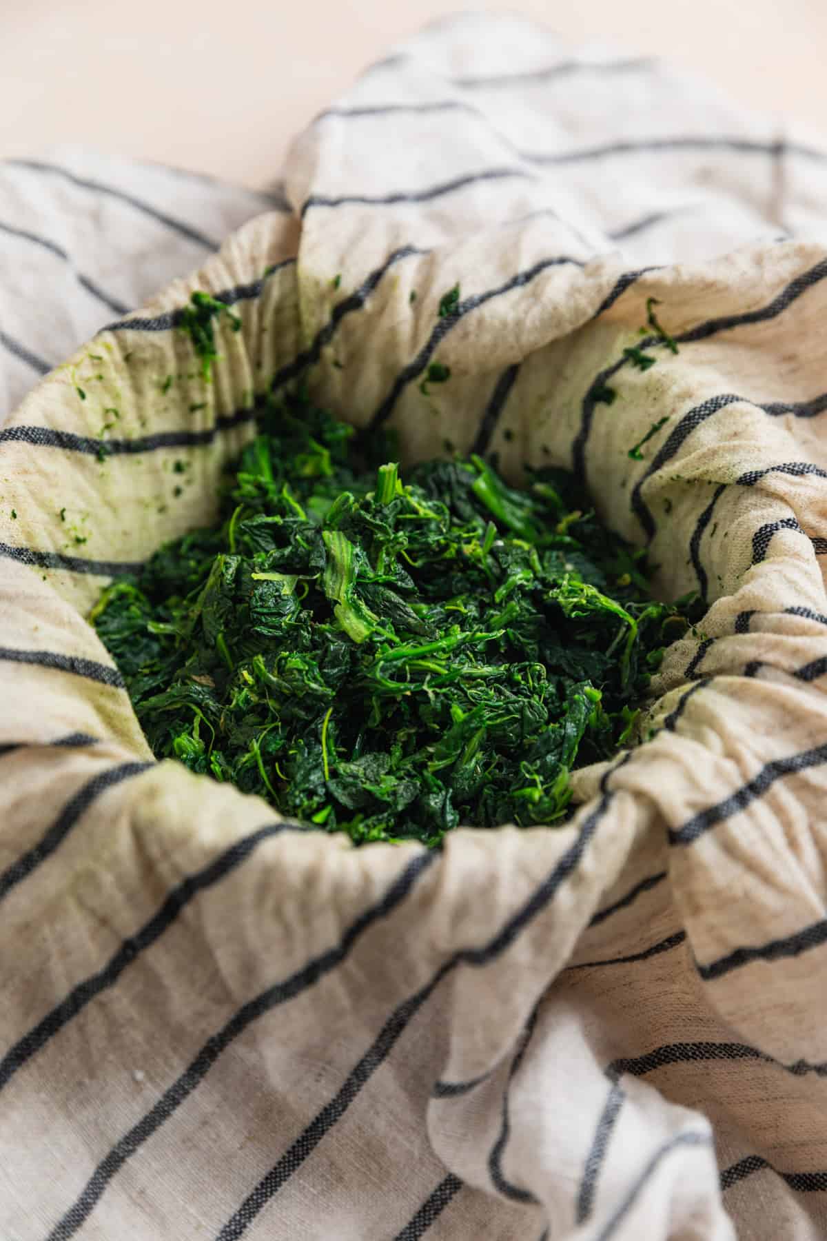 Spinach in towel drained of excess liquid.