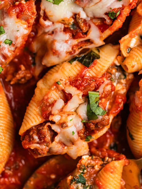 Ground beef stuffed shells in marinara with cheese and chopped basil over top.