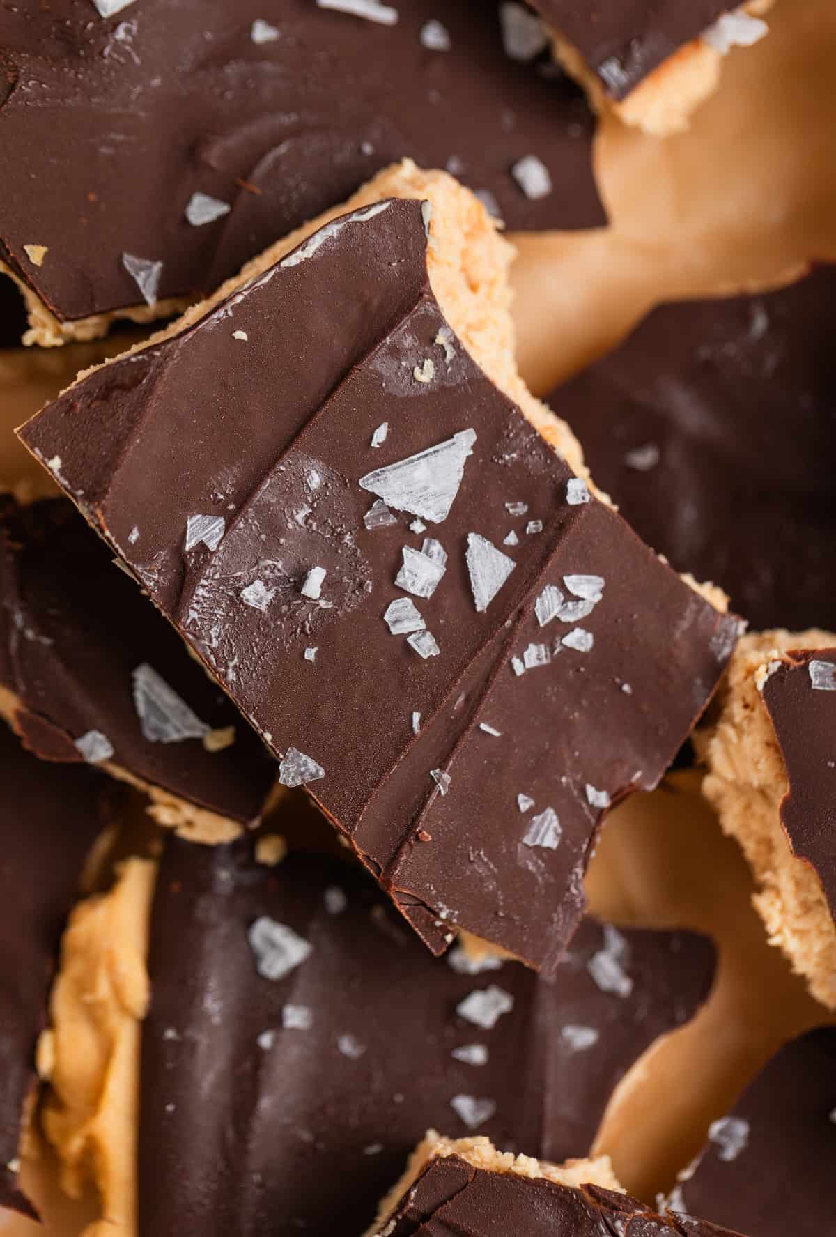 Close up of frozen chocolate covered peanut butter yogurt bark scattered on parchment paper.