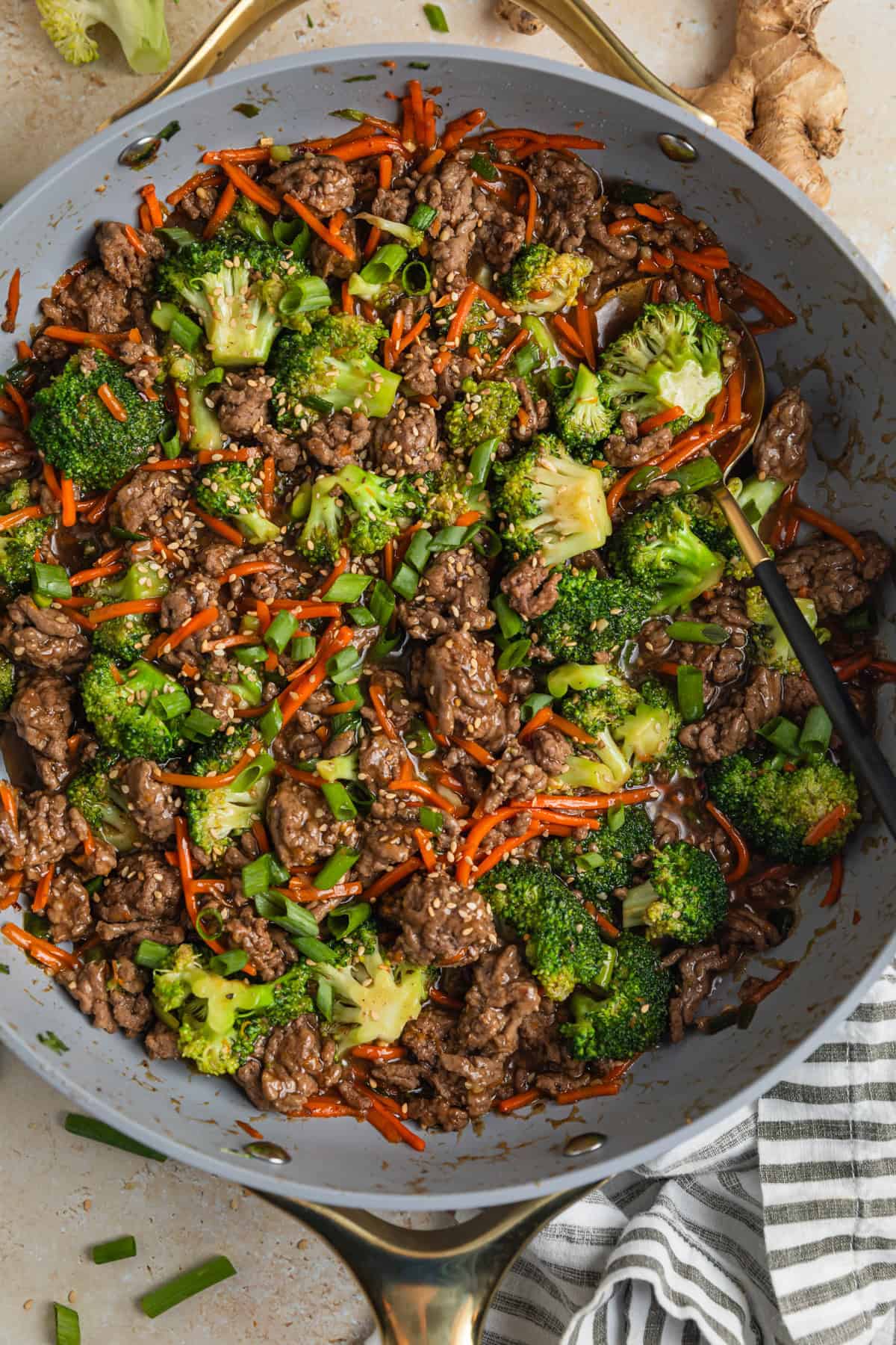 Ground beef teriyaki stir fry prepared in skillet topped with chopped green onions.