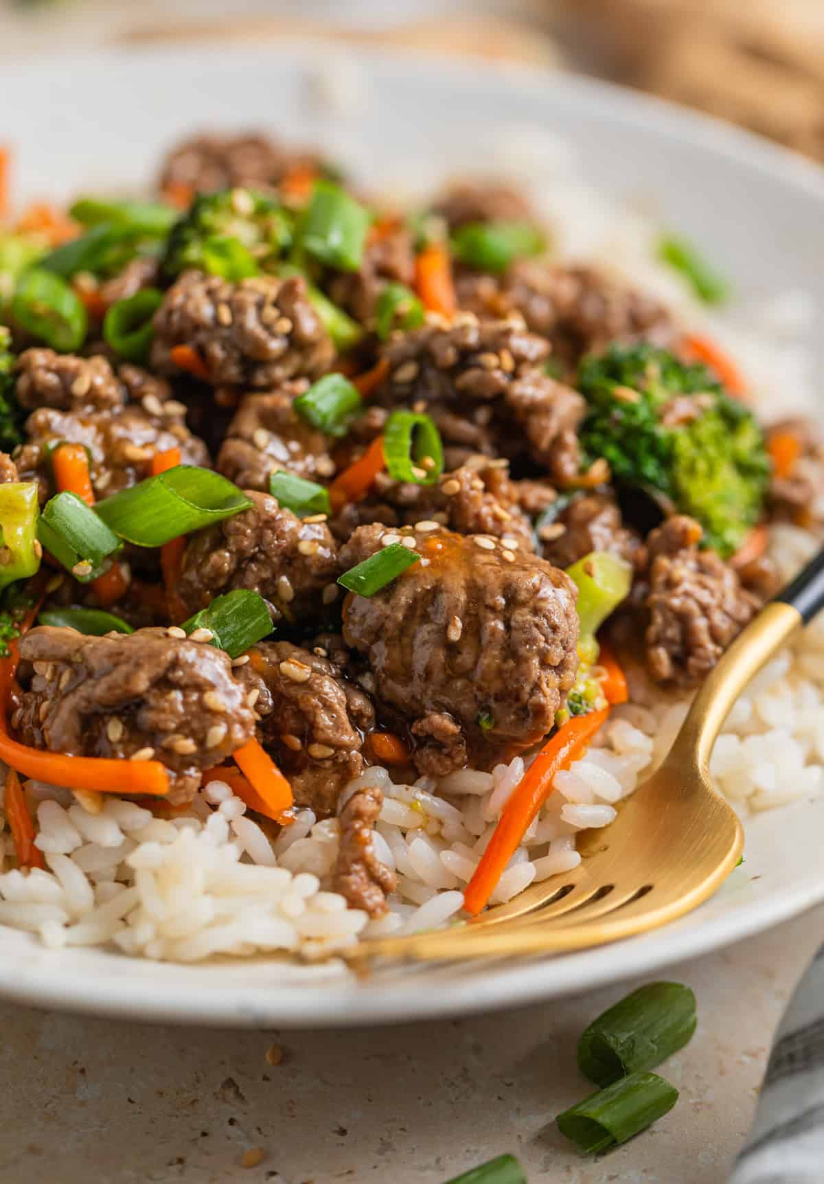 Clay plate with prepared beef stir fry over rice and topped with sesame seeds.