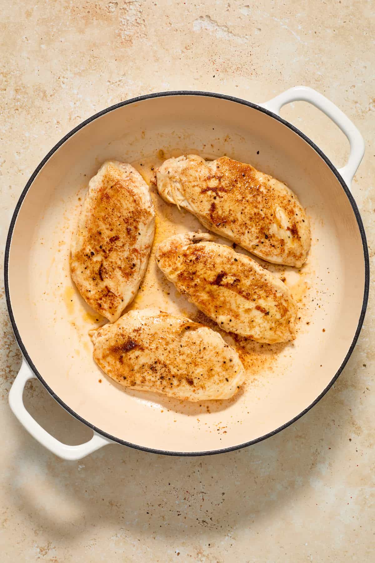 Seared chicken in skillet.