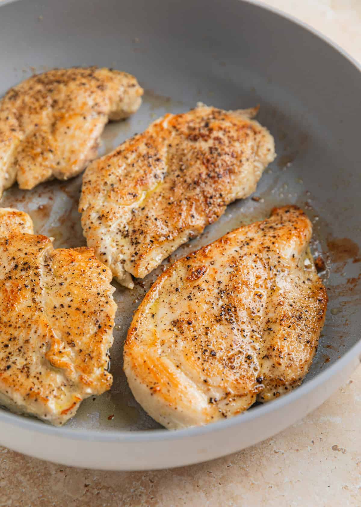 Seared chicken breast in skillet.