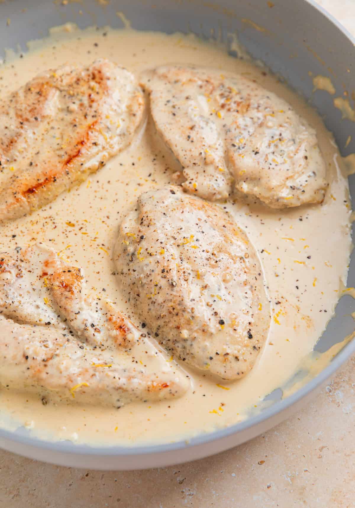 Chicken breasts in creamy lemon sauce in skillet.