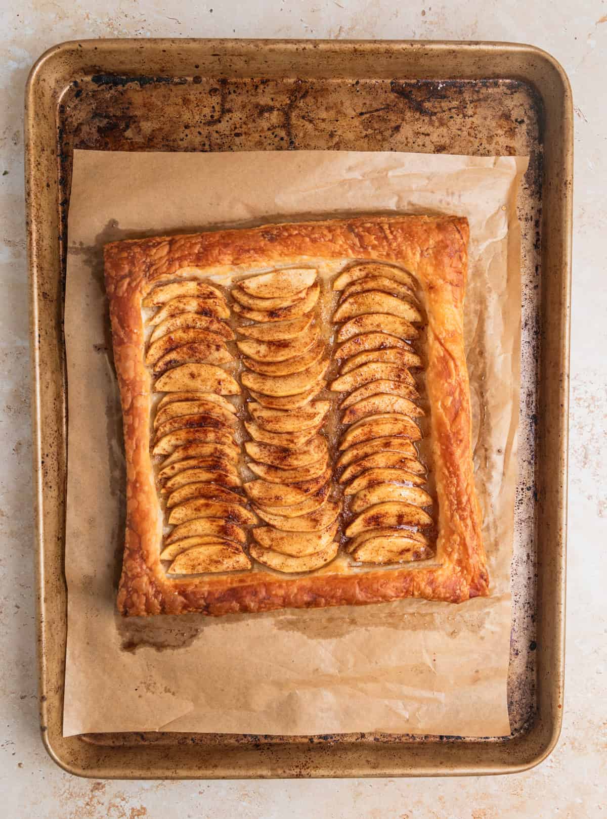 Apple tart baked with honey brushed to glaze the apples on baking sheet.