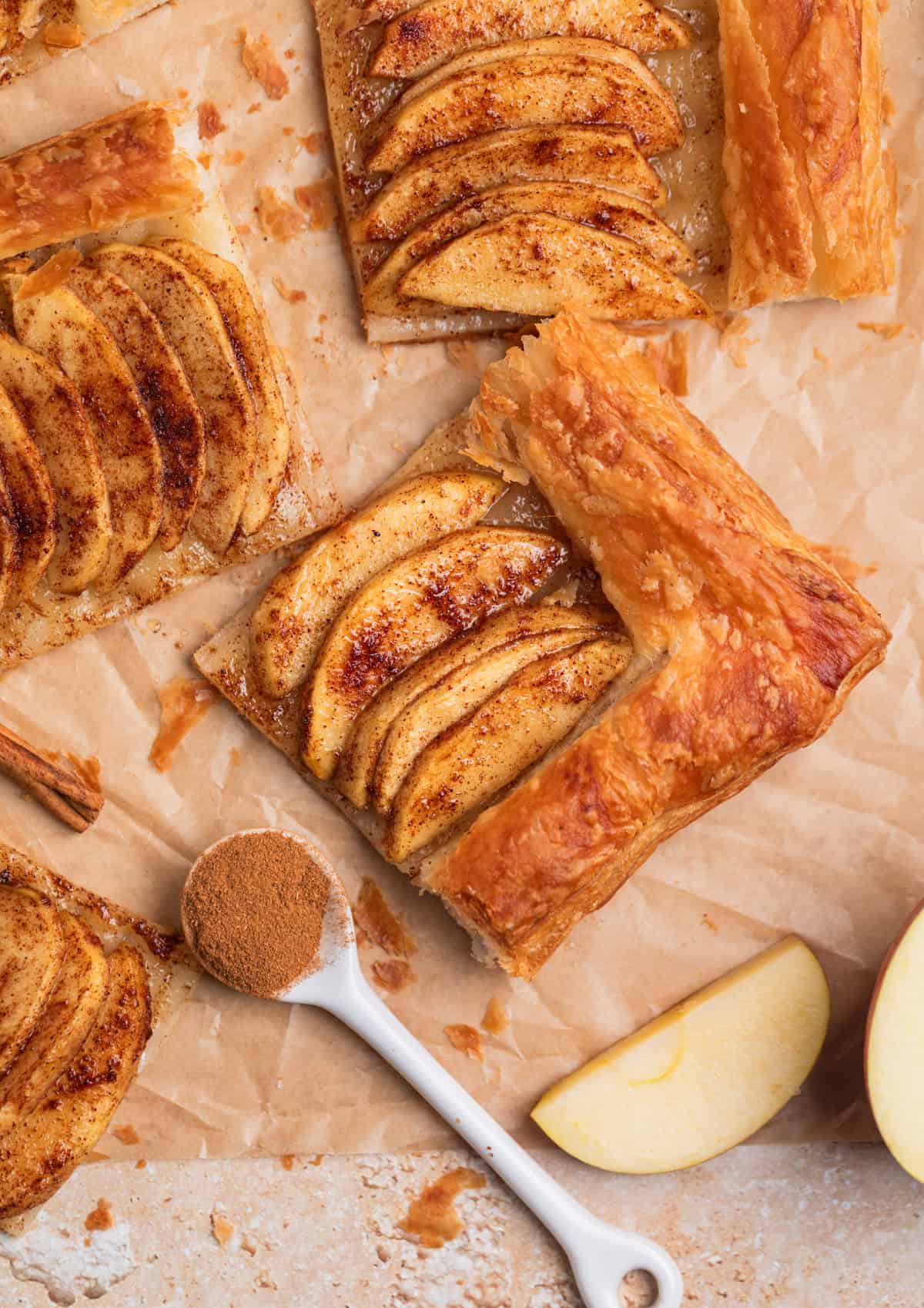 Puff pastry cinnamon apple tarts arranged on parchment.