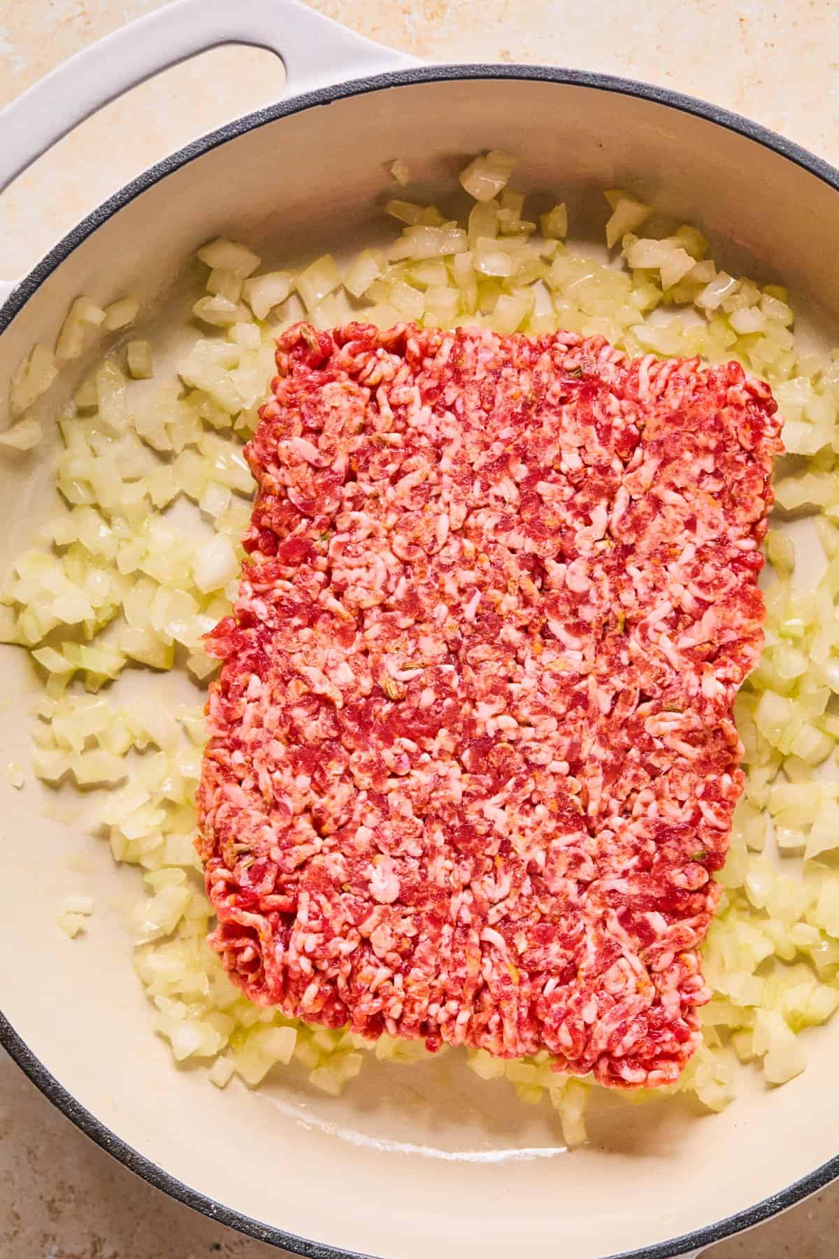 Italian sausage added to skillet with softened onions.