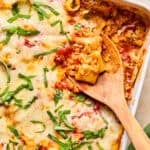 Pasta bake with Italian sausage in pan with spoon scooping in.