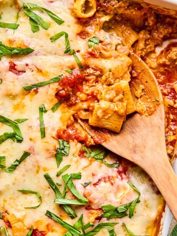 Pasta bake with Italian sausage in pan with spoon scooping in.