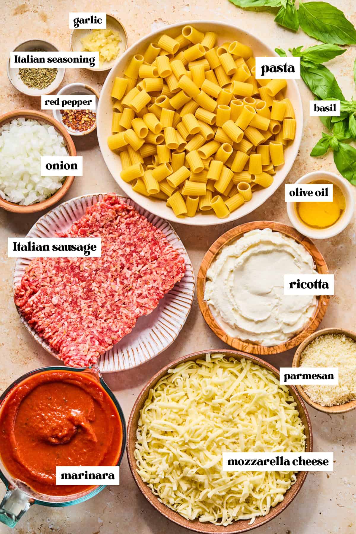 Pasta, meat, basil and other ingredients arranged on surface prepped for recipe.