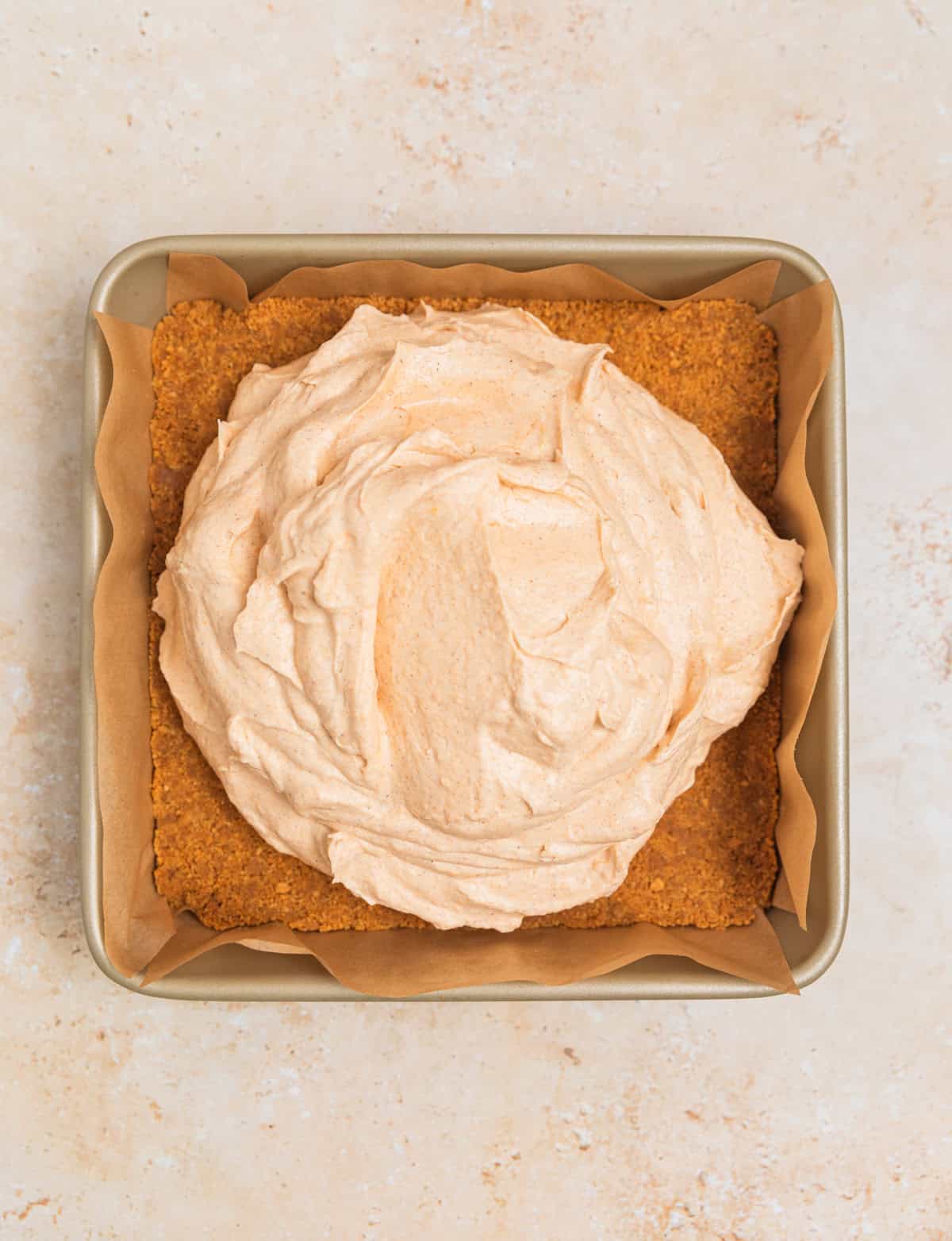 Pumpkin cheesecake filling added to Ginger snap cookie crust in square pan.