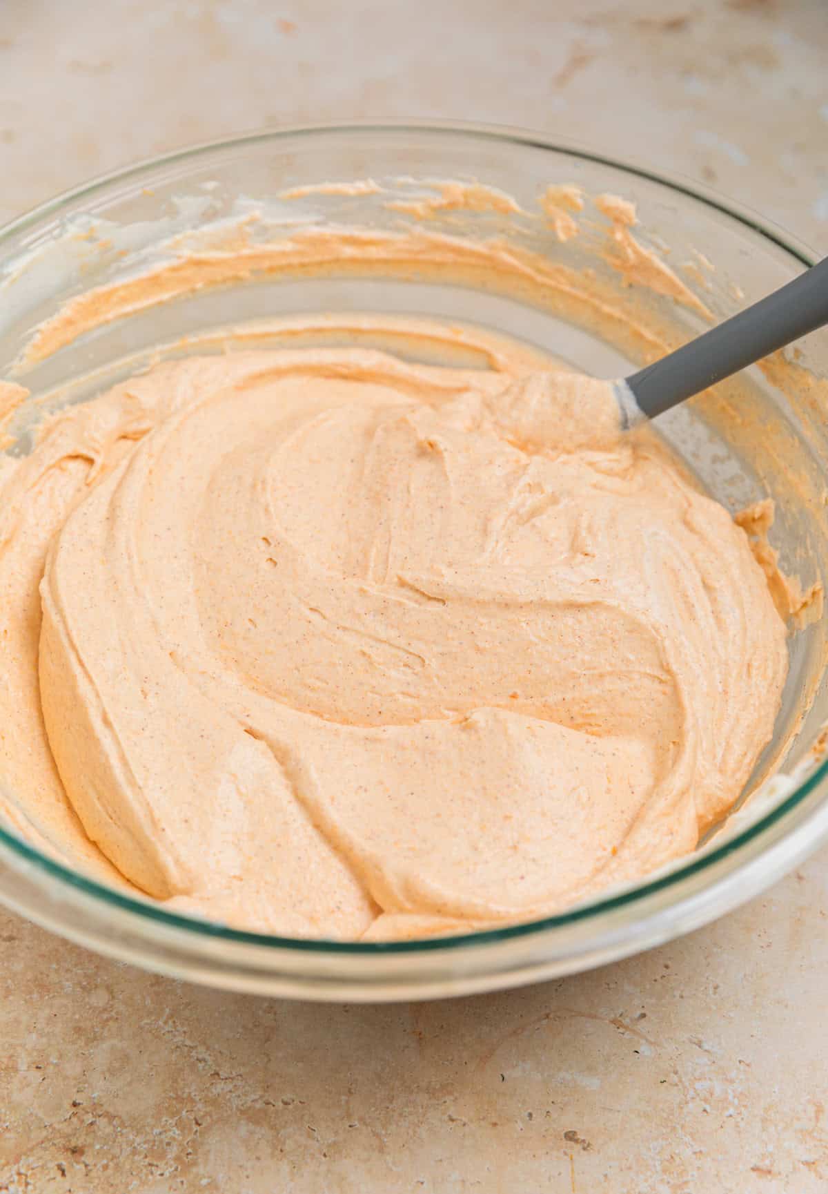 No bake pumpkin cheesecake filling in bowl with gray spatula.