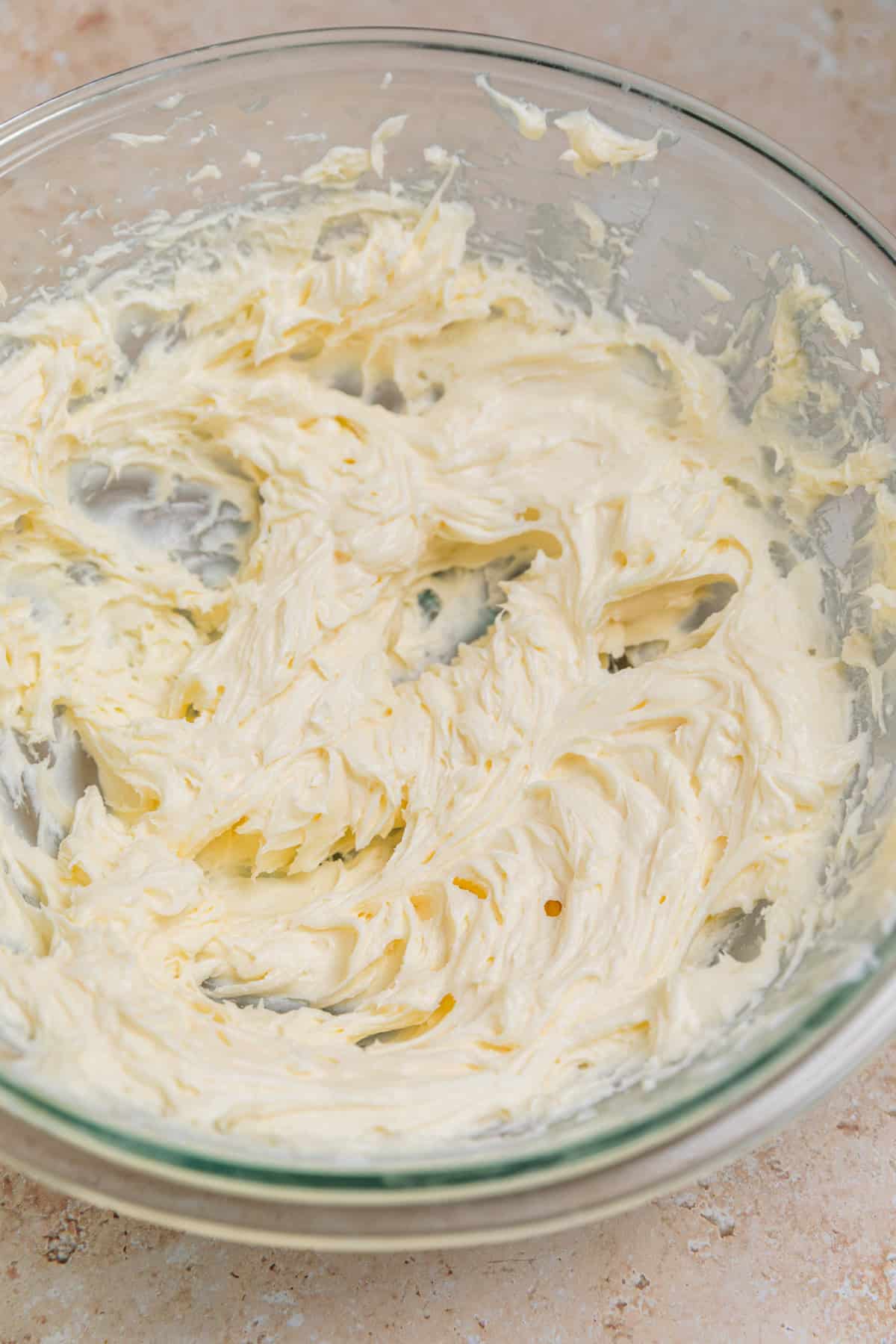 Creamed sugar and cream cheese in glass mixing bowl.