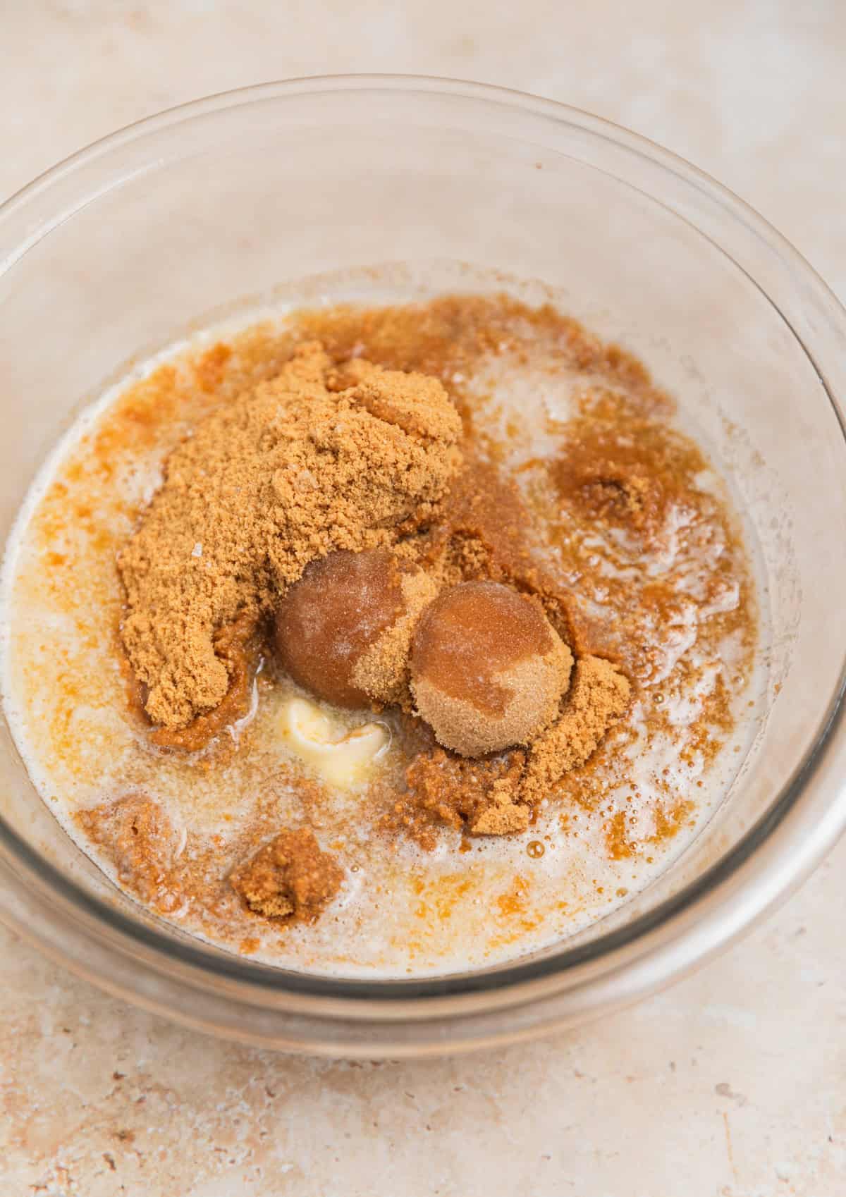 Brown sugar and melted butter in glass bowl with cookie crumbs.