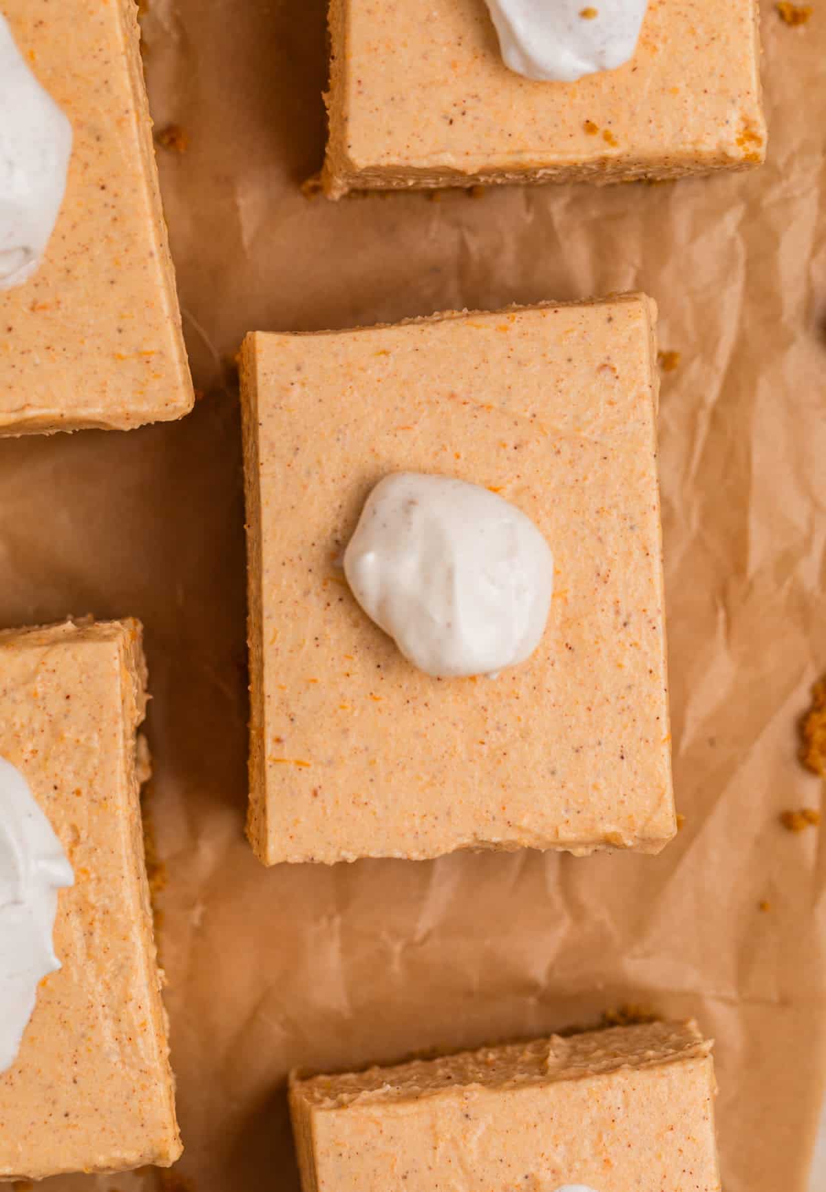 Overhead view of slices of pumpkin cheesecake topped with whipped cream.