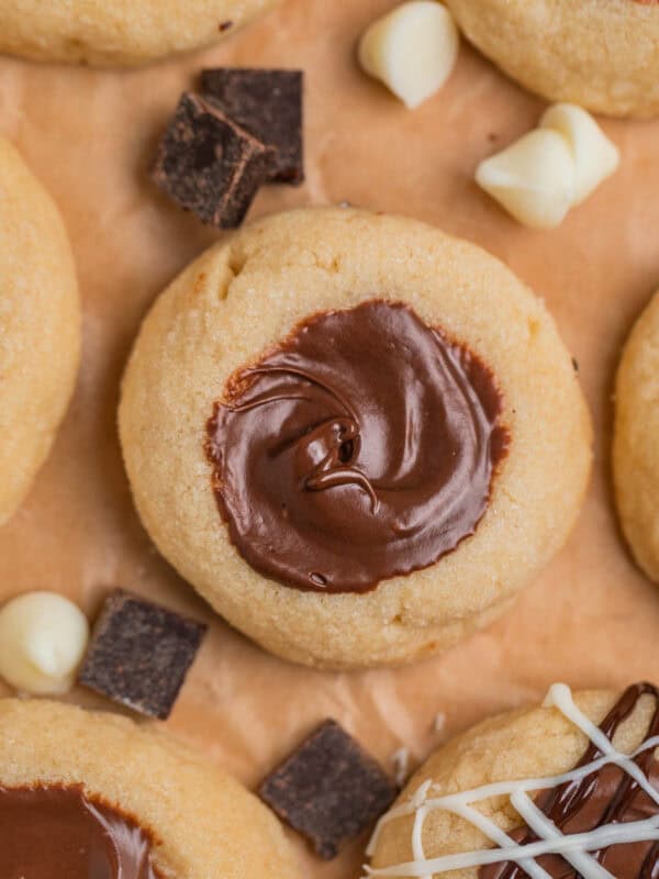 Nutella cookies arranged on parchment with white and dark chocolate chips arranged around the cookies.