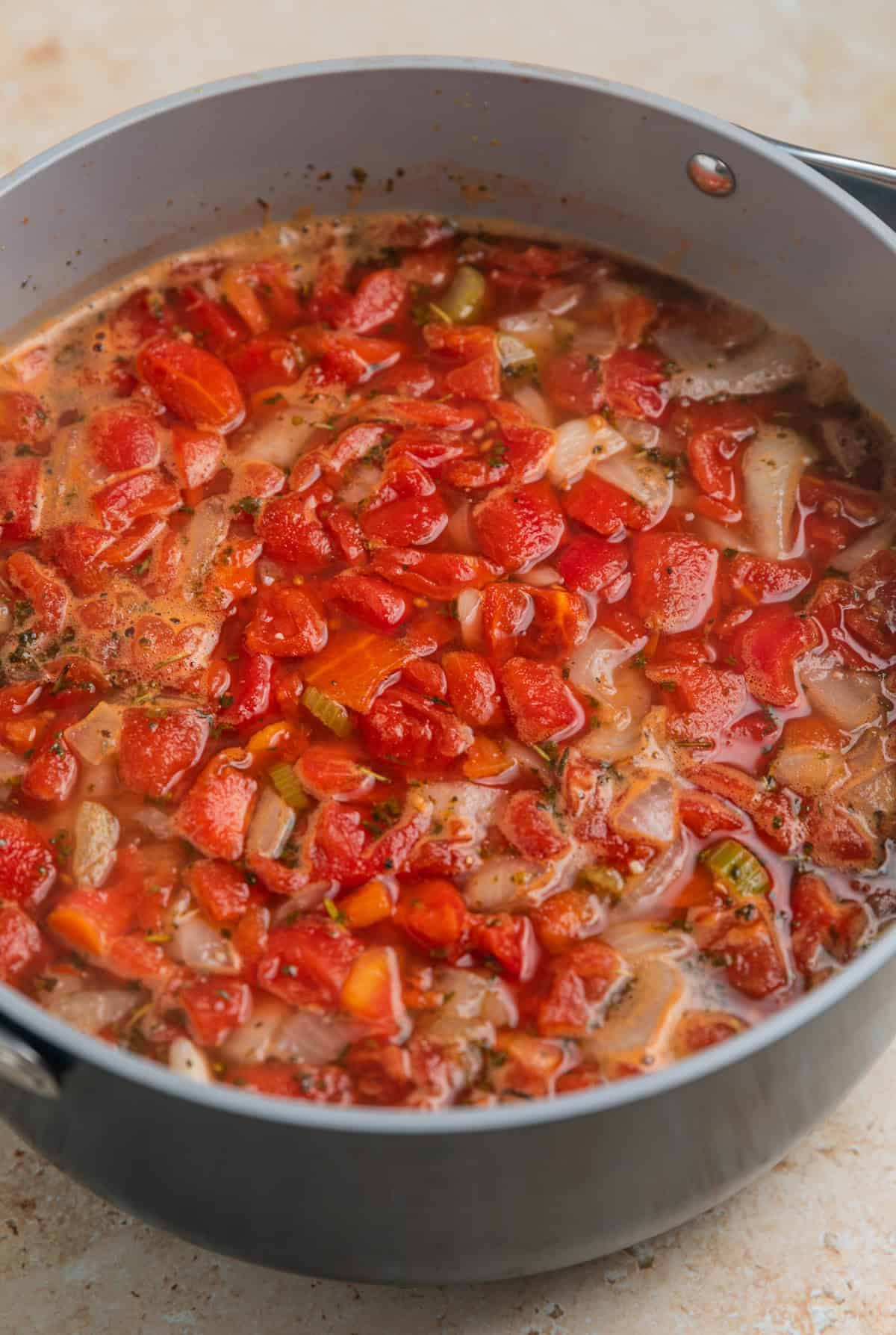 Vegetable meatball soup in pot after simmering with tomatoes, broth and parmesan rind.