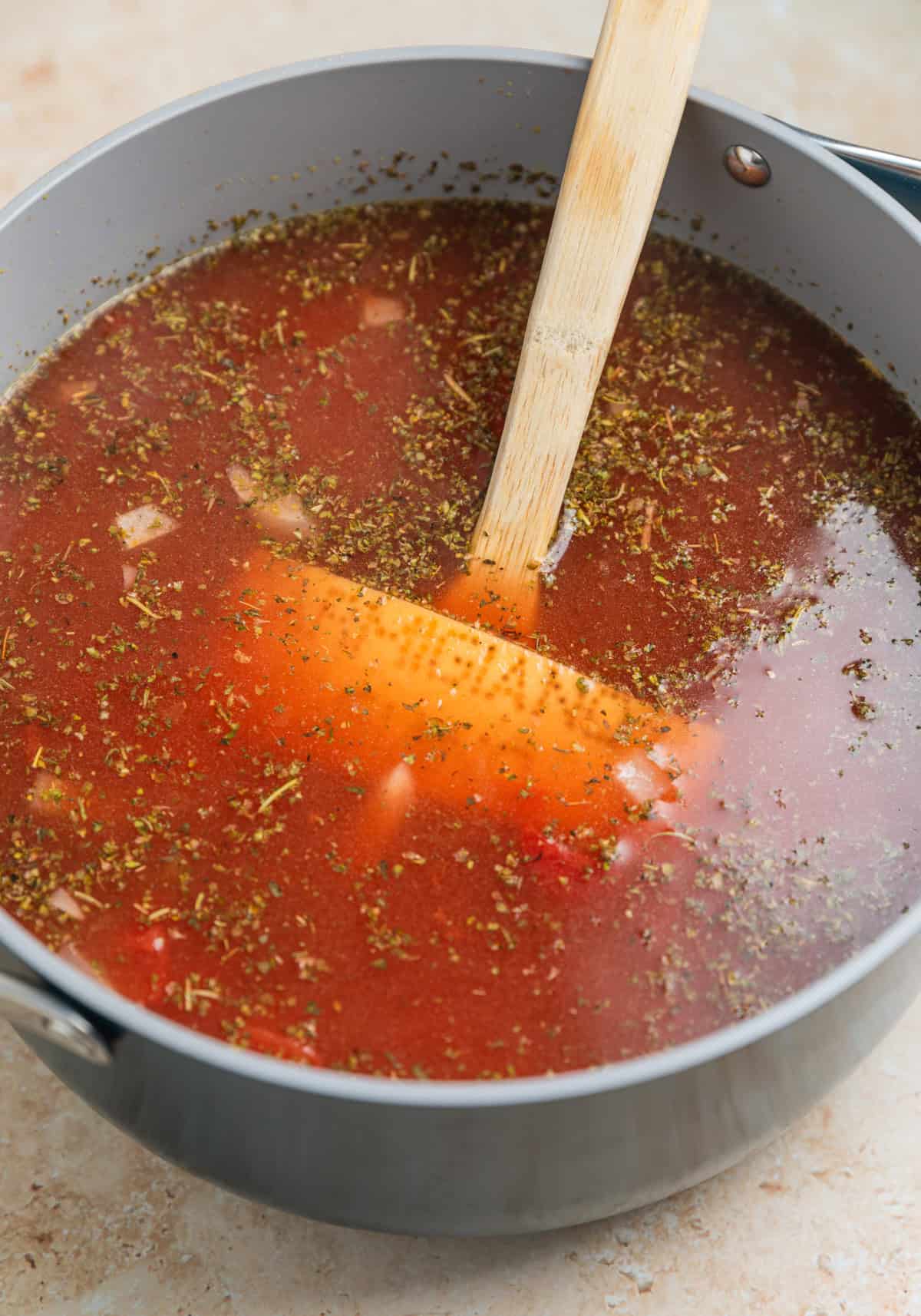 Broth and soup ingredients added to pot with parmesan rind.