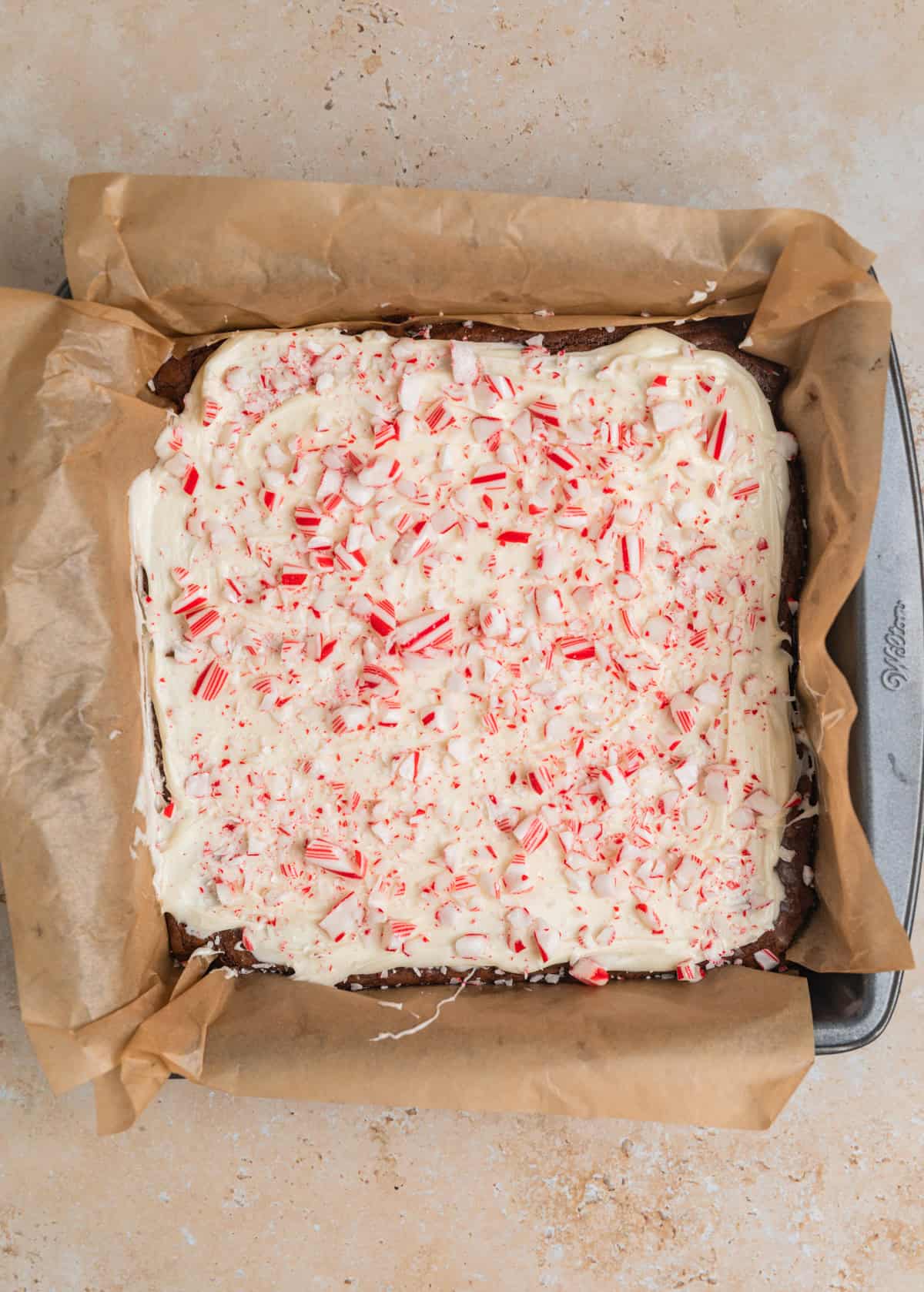 Crushed candy canes sprinkled over top of brownies covered in white chocolate.