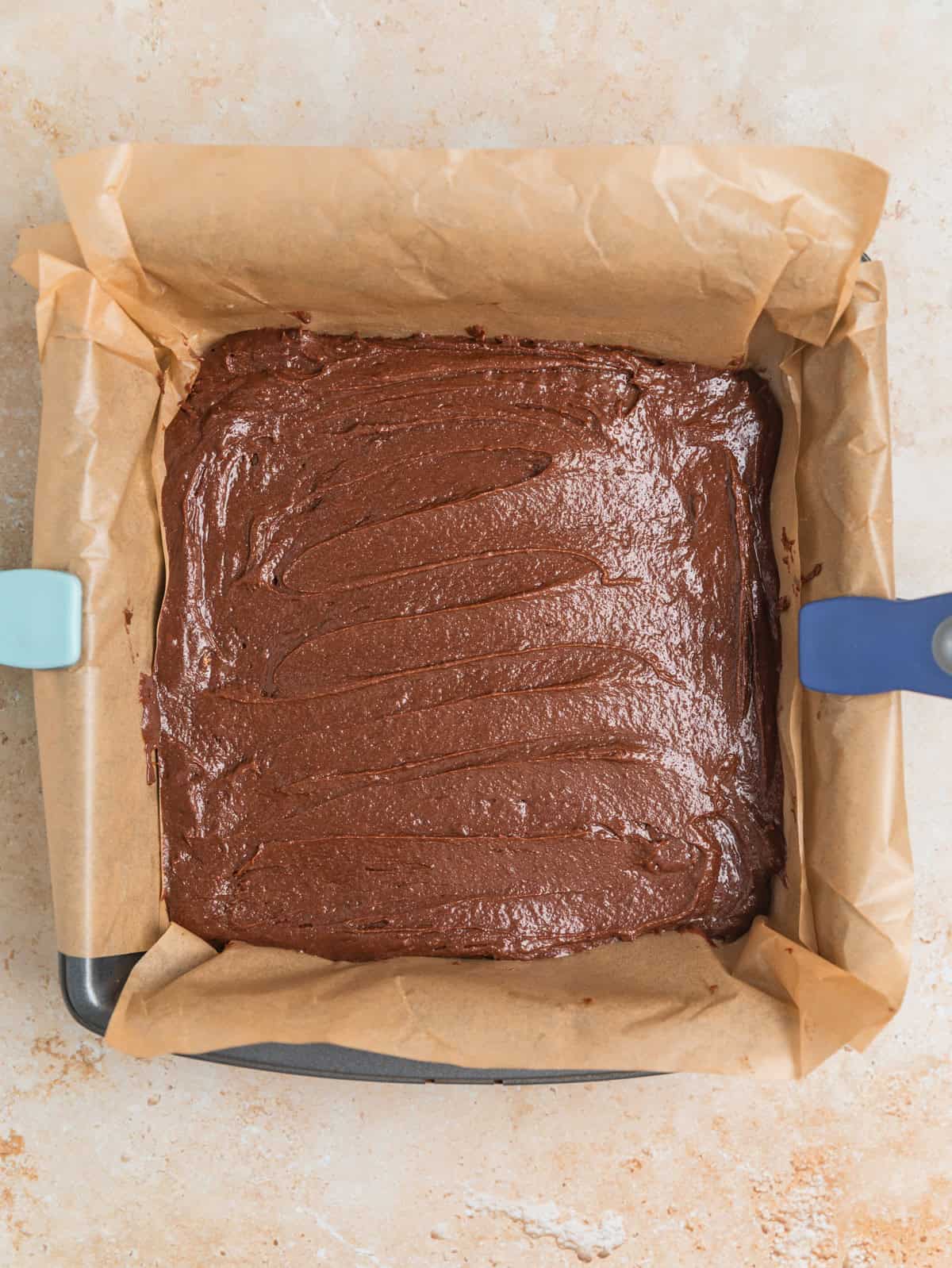 Peppermint bark brownie batter in parchment lined pan.