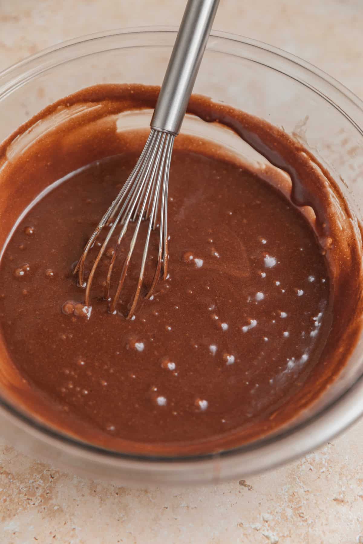 Melted chocolate mixed in bowl with whisk.