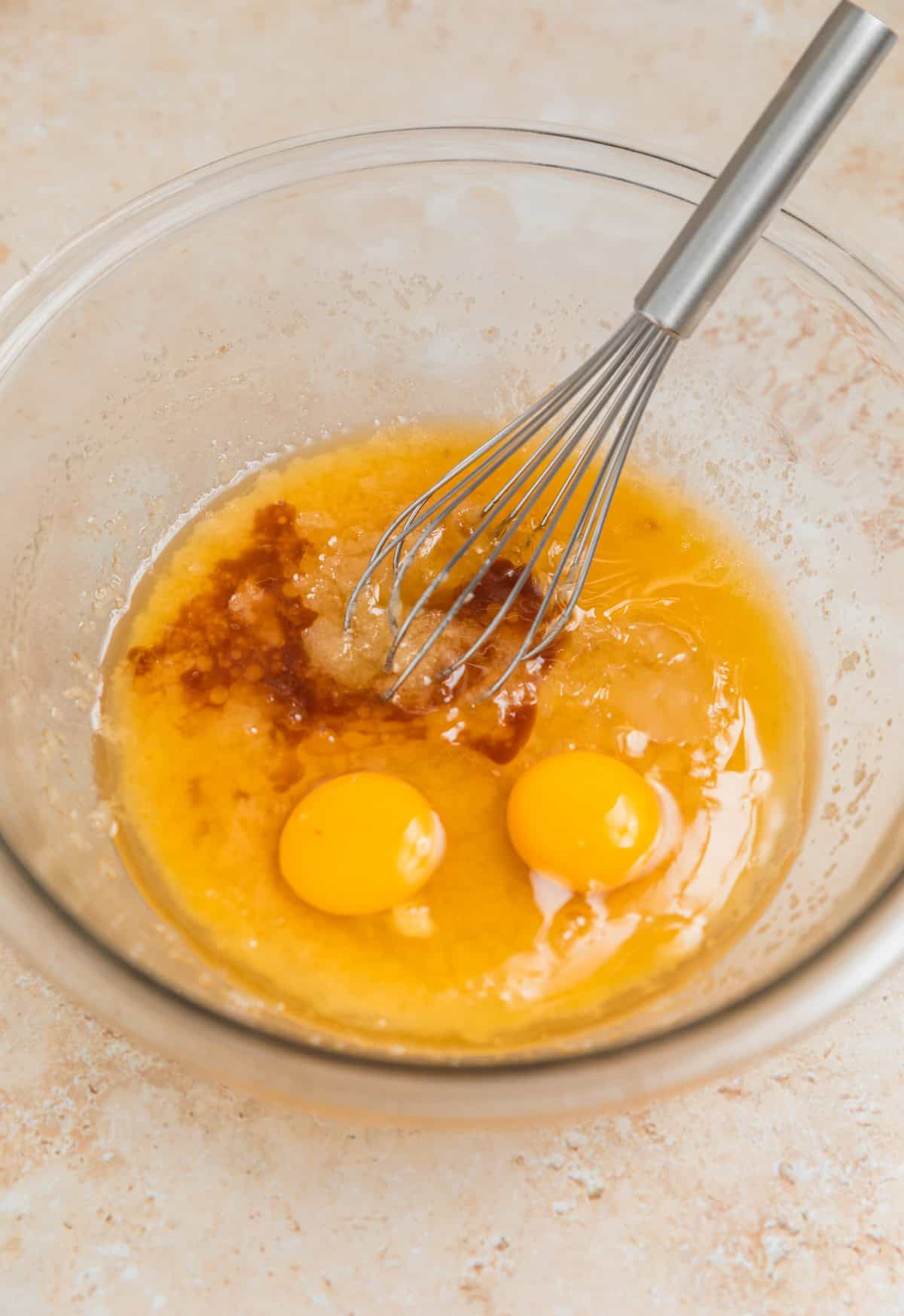 Eggs and vanilla added to mixing bowl with whisk.
