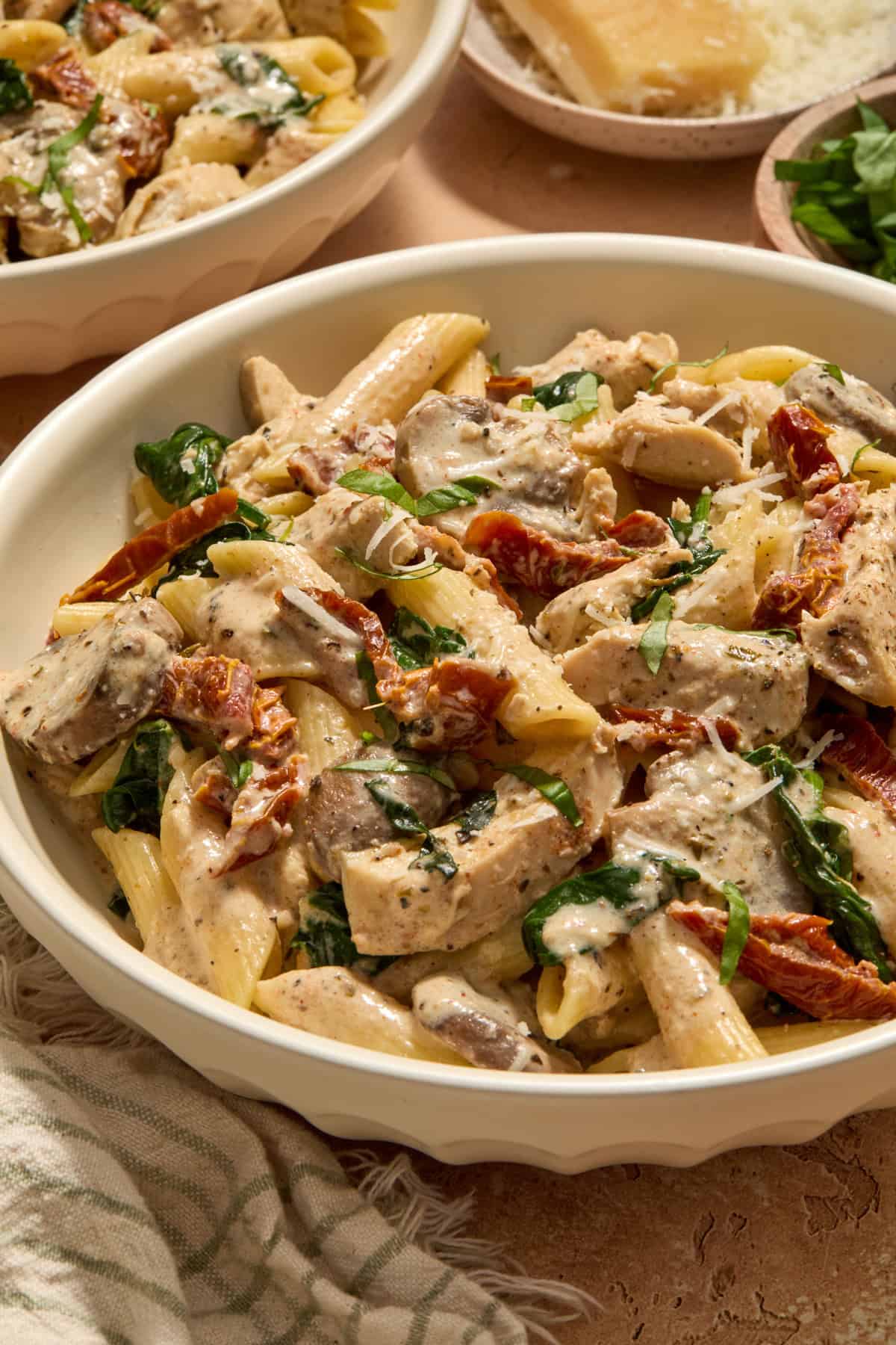 Bowl of creamy slow cooker chicken pasta topped with fresh basil and parmesan.