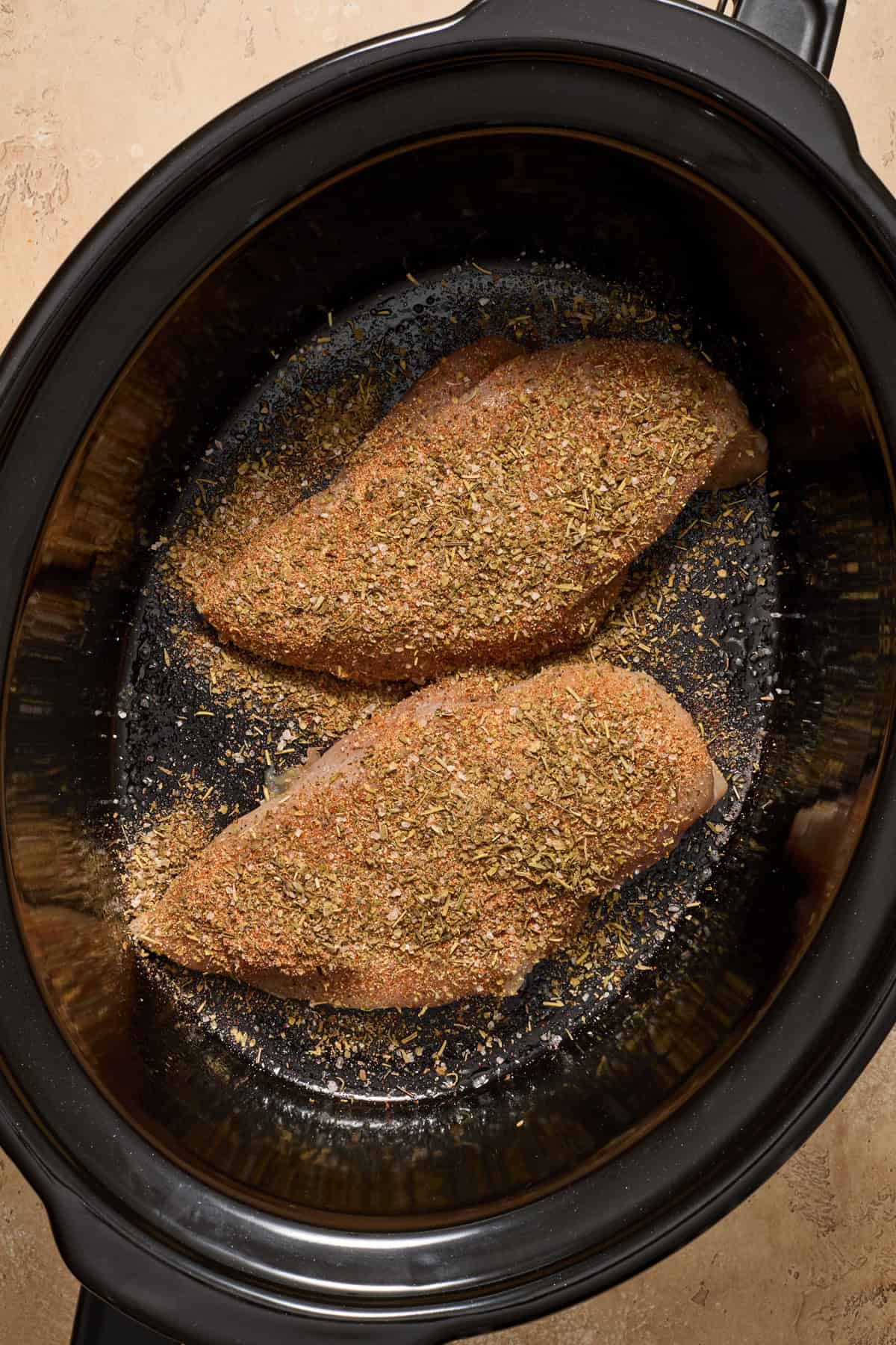 Crockpot with seasoned chicken breast.
