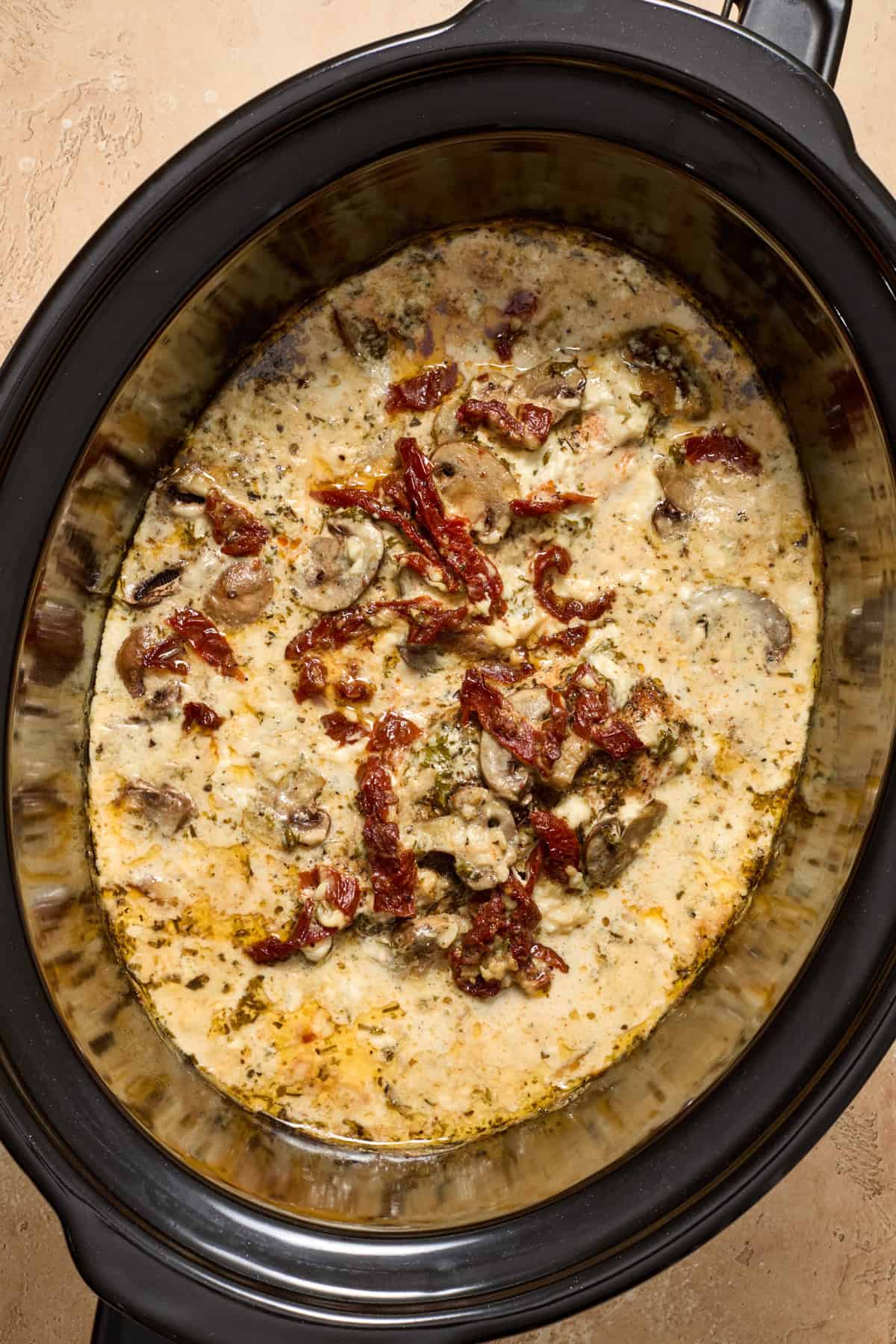 Cooked creamy chicken with mushrooms in crockpot.