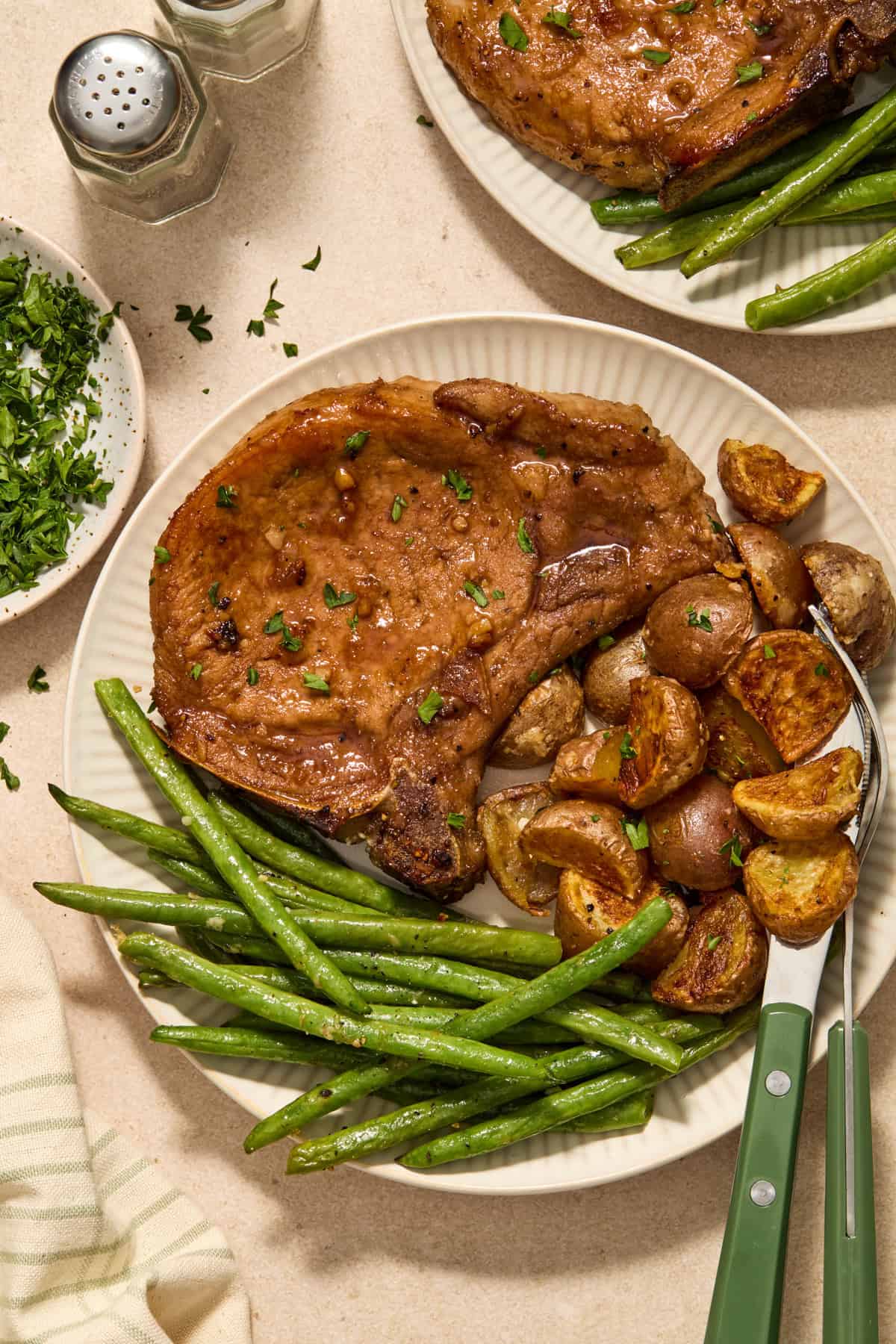 Plate with honey garlic pork chops, green beans and potatoes.