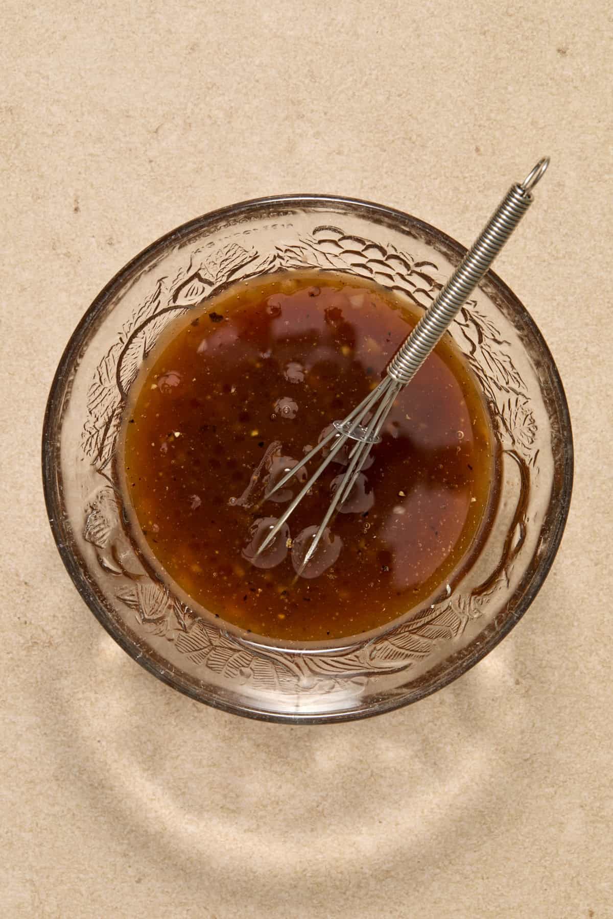 Honey garlic marinade in bowl with whisk.