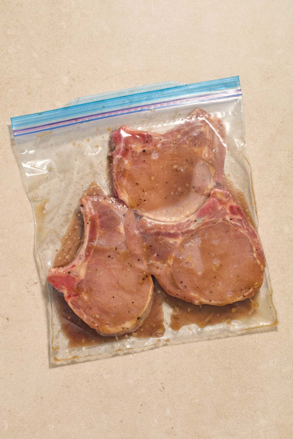 Bone-in pork chops in plastic bag with marinade.