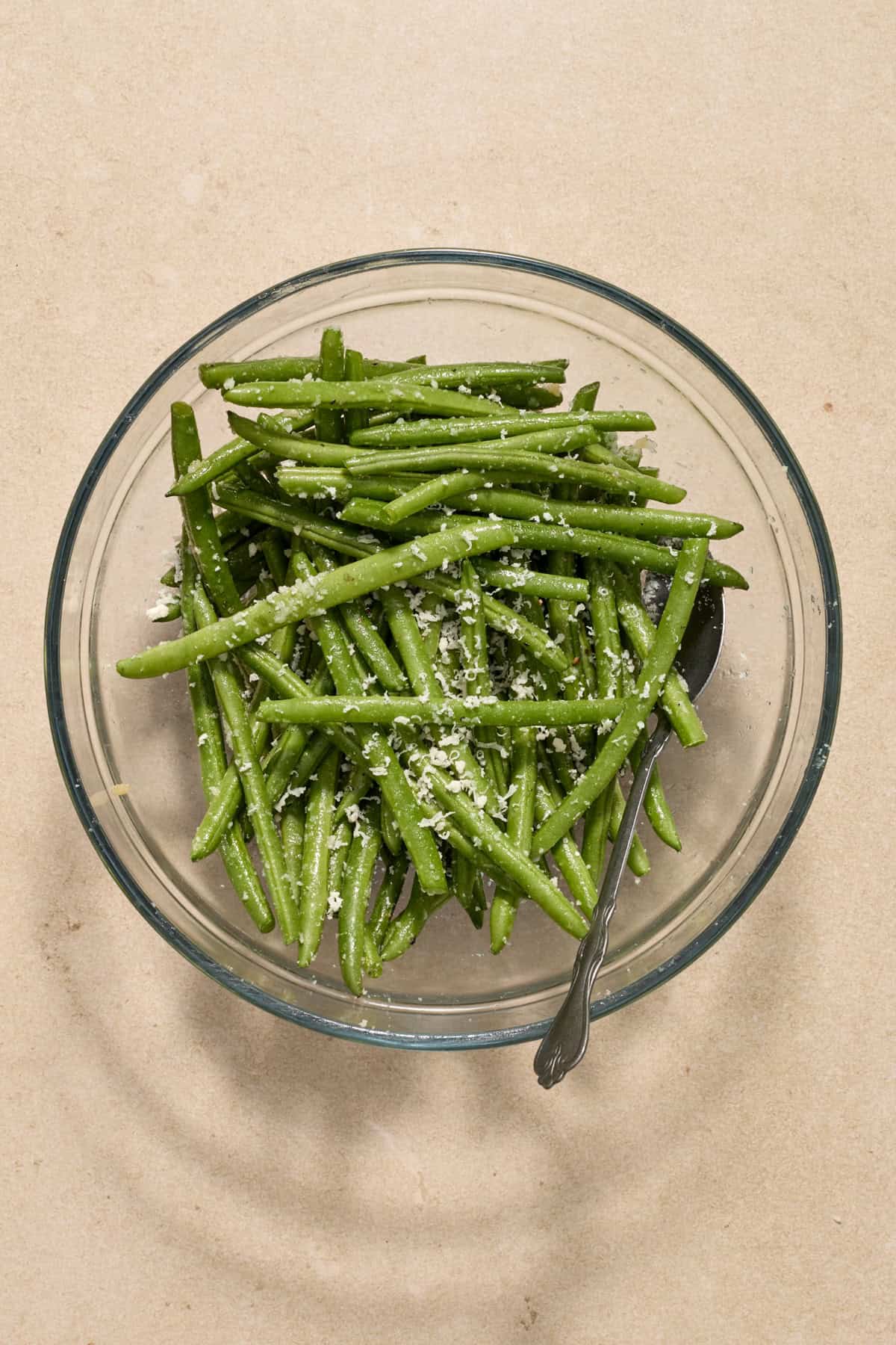 Green beans tossed in parmesan and seasoning in bowl.