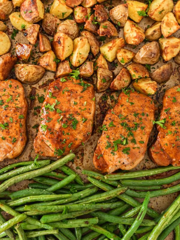 Sheet pan with cooked pork chops, potatoes and green beans.