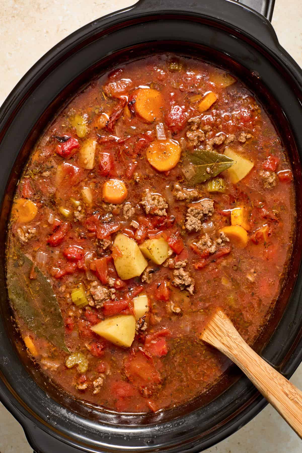 Cooked slow cooker hamburger soup with spoon.