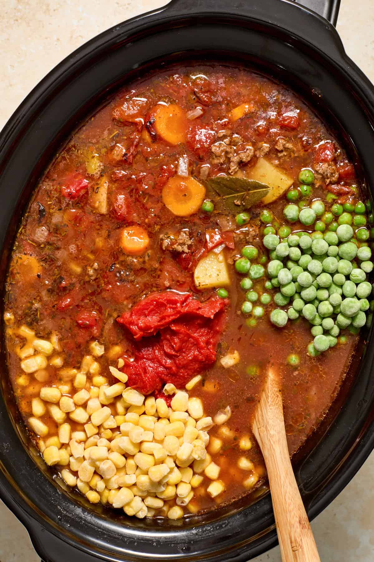 Peas, corn and tomato paste added to soup in crockpot.