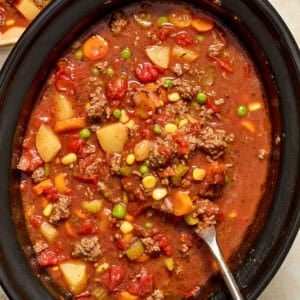 Crockpot with ladle spooning out hamburger vegetable soup.