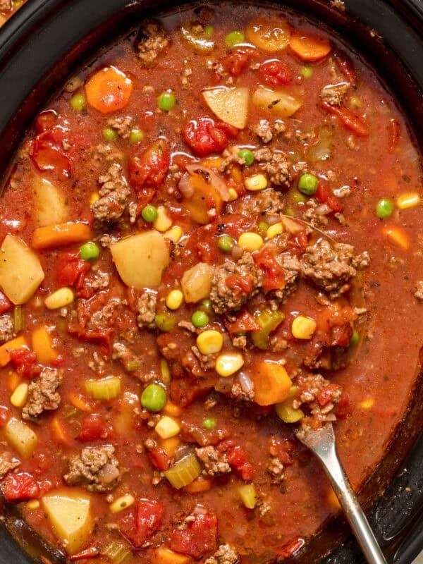 Crockpot with ladle spooning out hamburger vegetable soup.